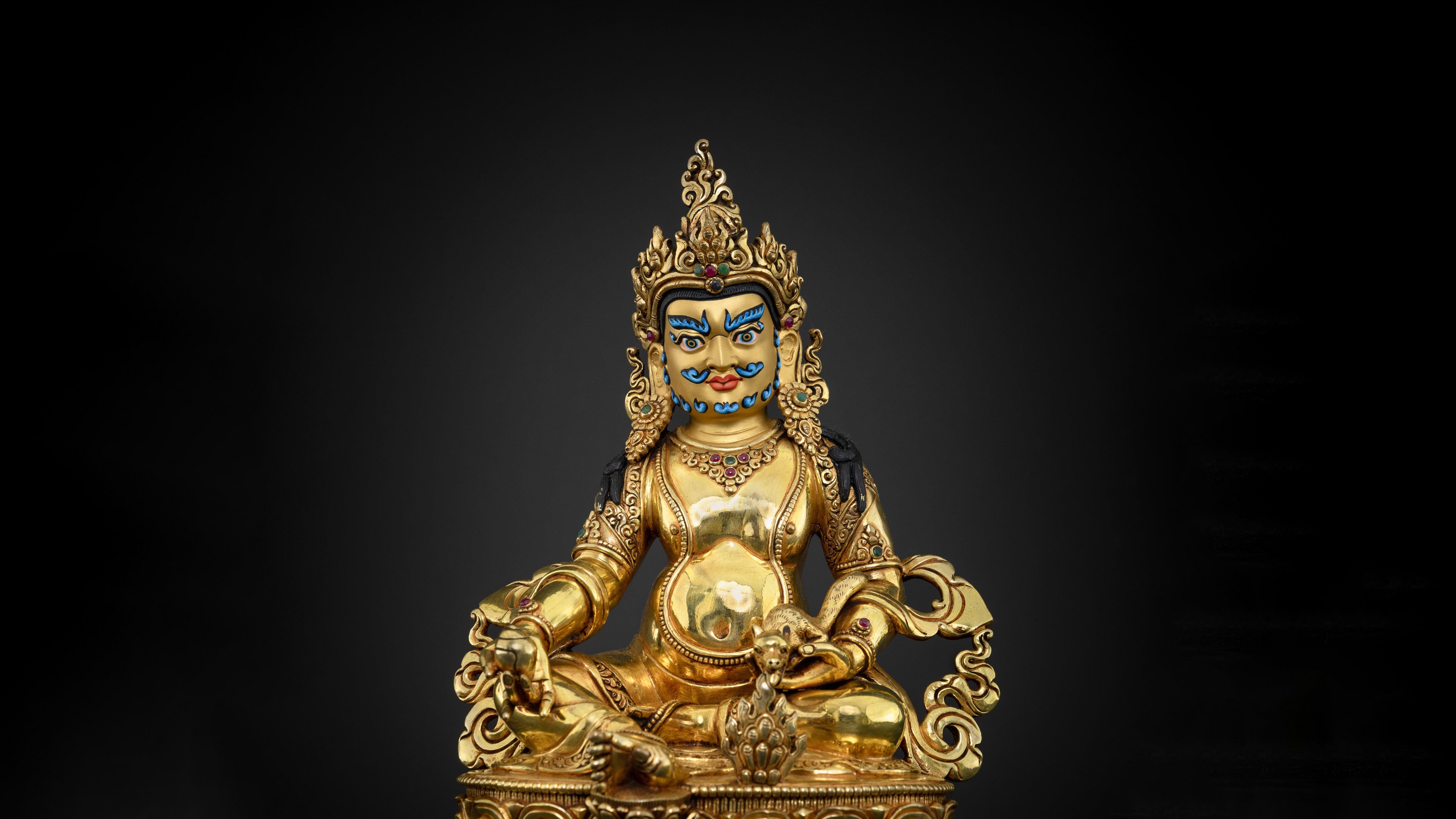 golden statue of a wealth deity with intricate designs and adorned with gemstones