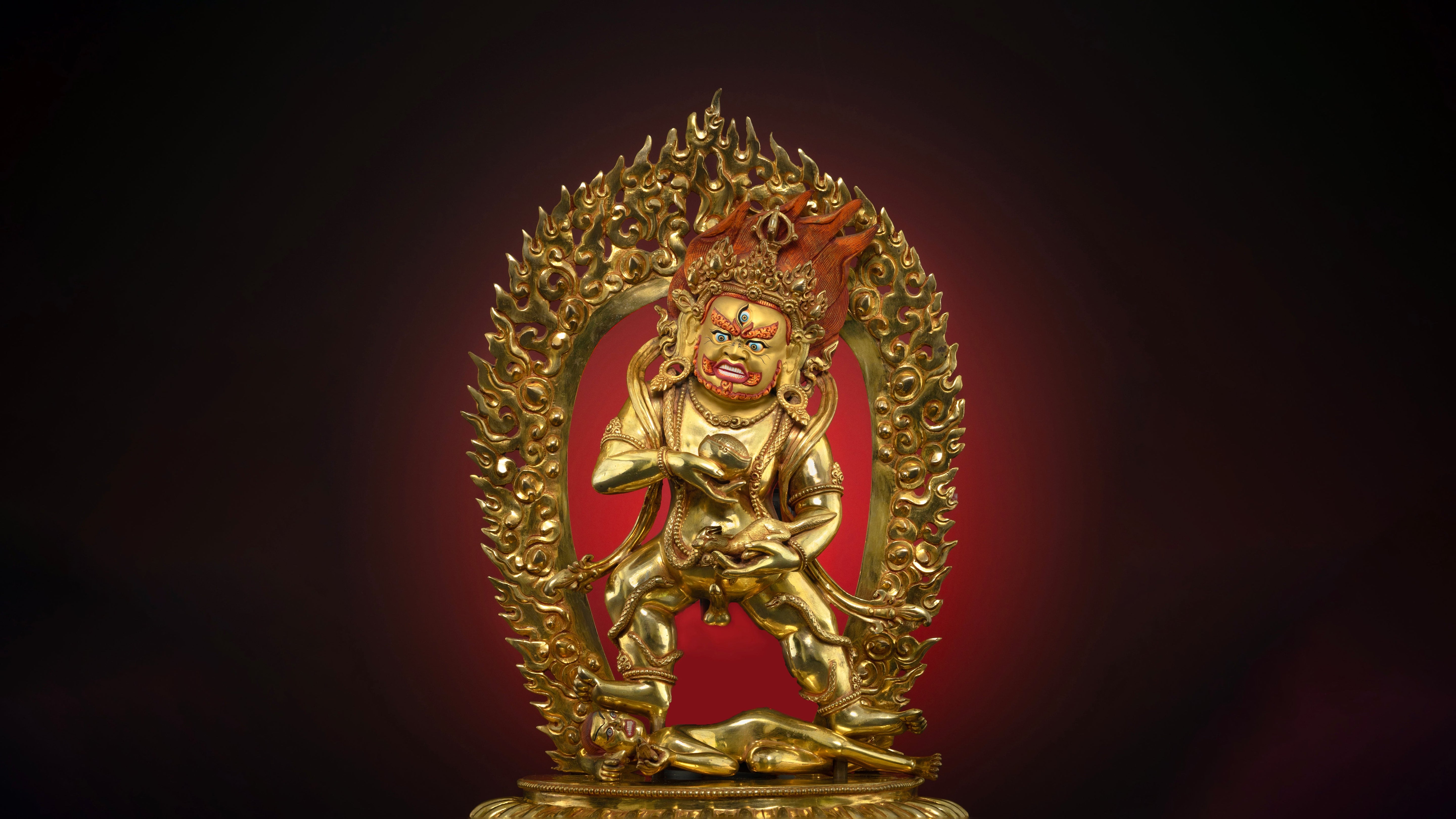 Masterpiece statue of Black Dzambhala with a fire backdrop in front of a dark background