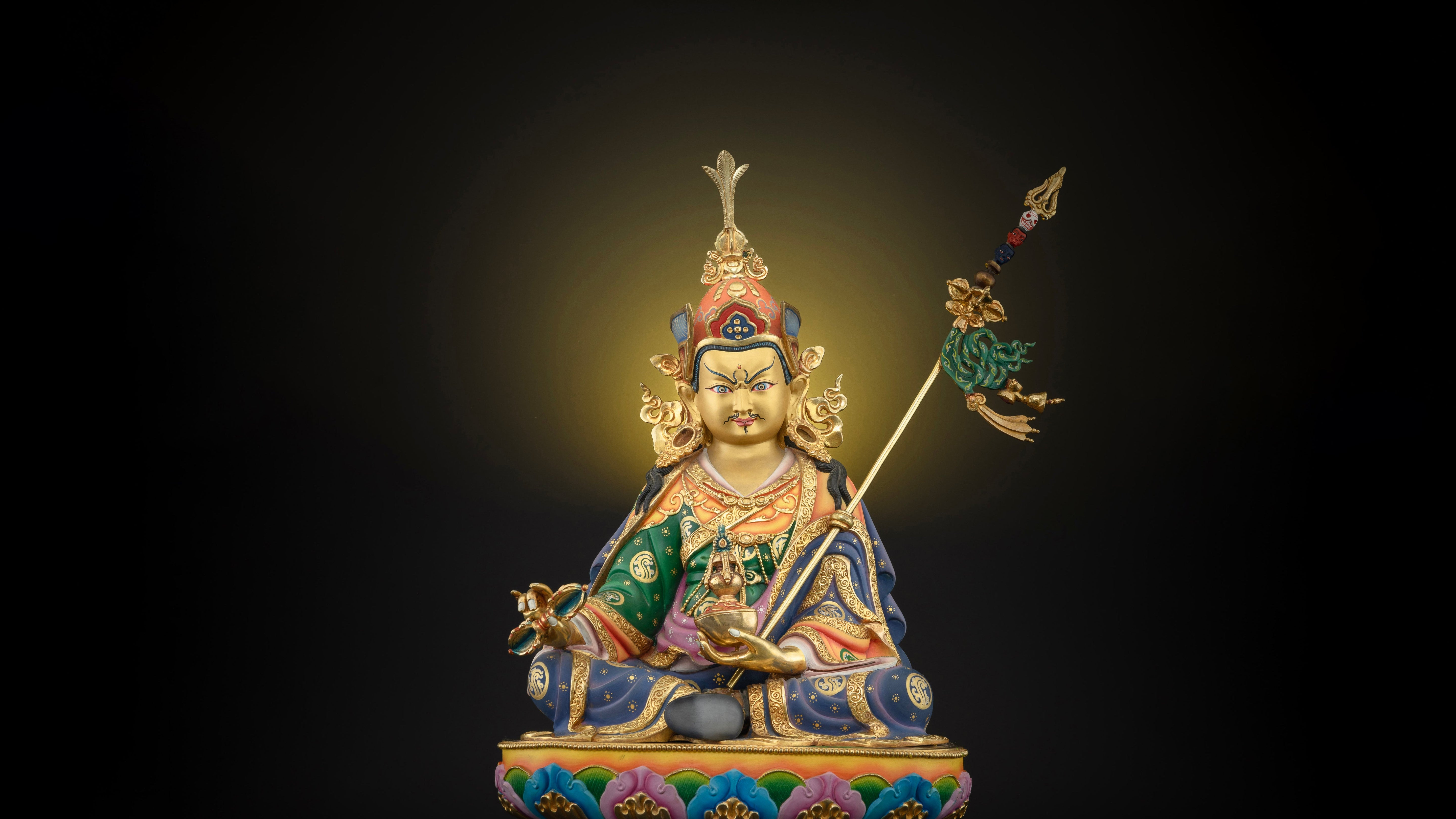 golden Guru RInpoche statue with blue and green colored in many places and adorned with semi precious gemstones