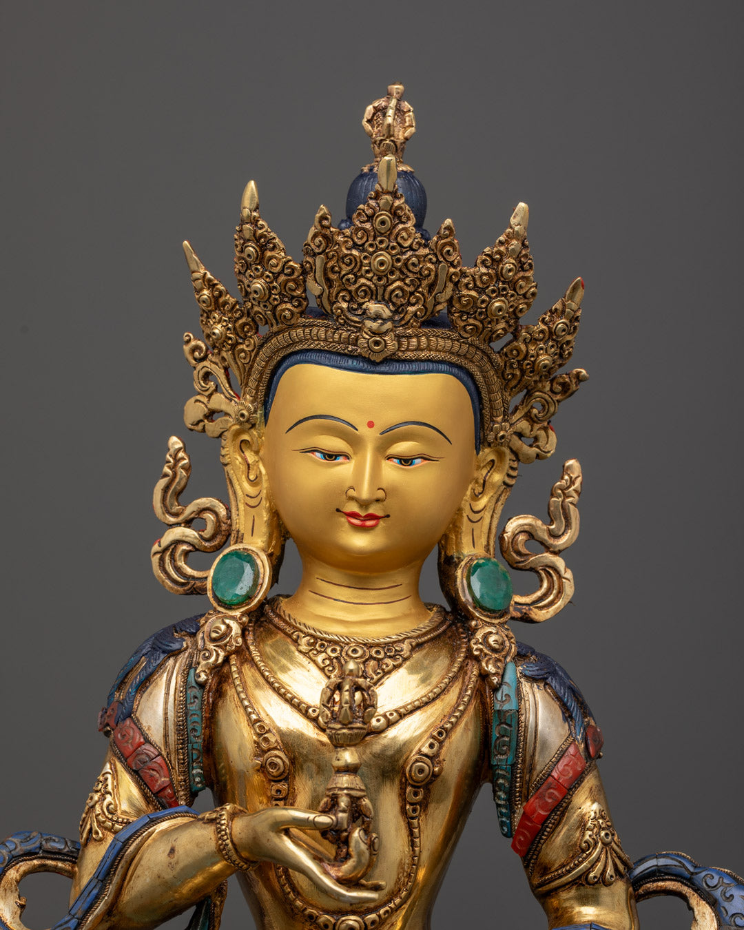 24k gold-gilded face of Vajrasattva statue with intricately painted details and semi-precious stone-inlaid jewelry, symbolizing purification and wisdom