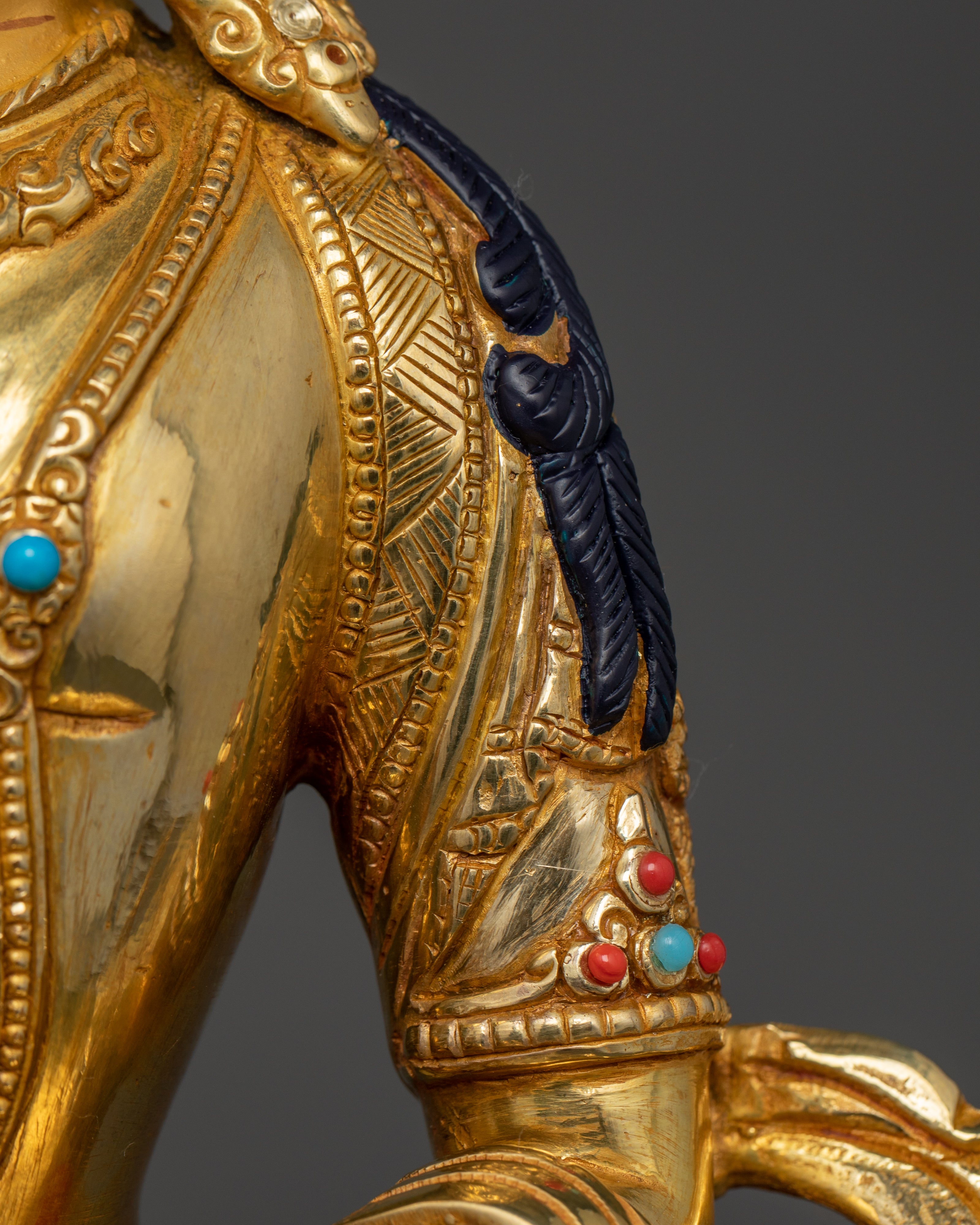 the gold plated arm of Amitayus Hayagriva statue with parts of acrylic colored hair visible