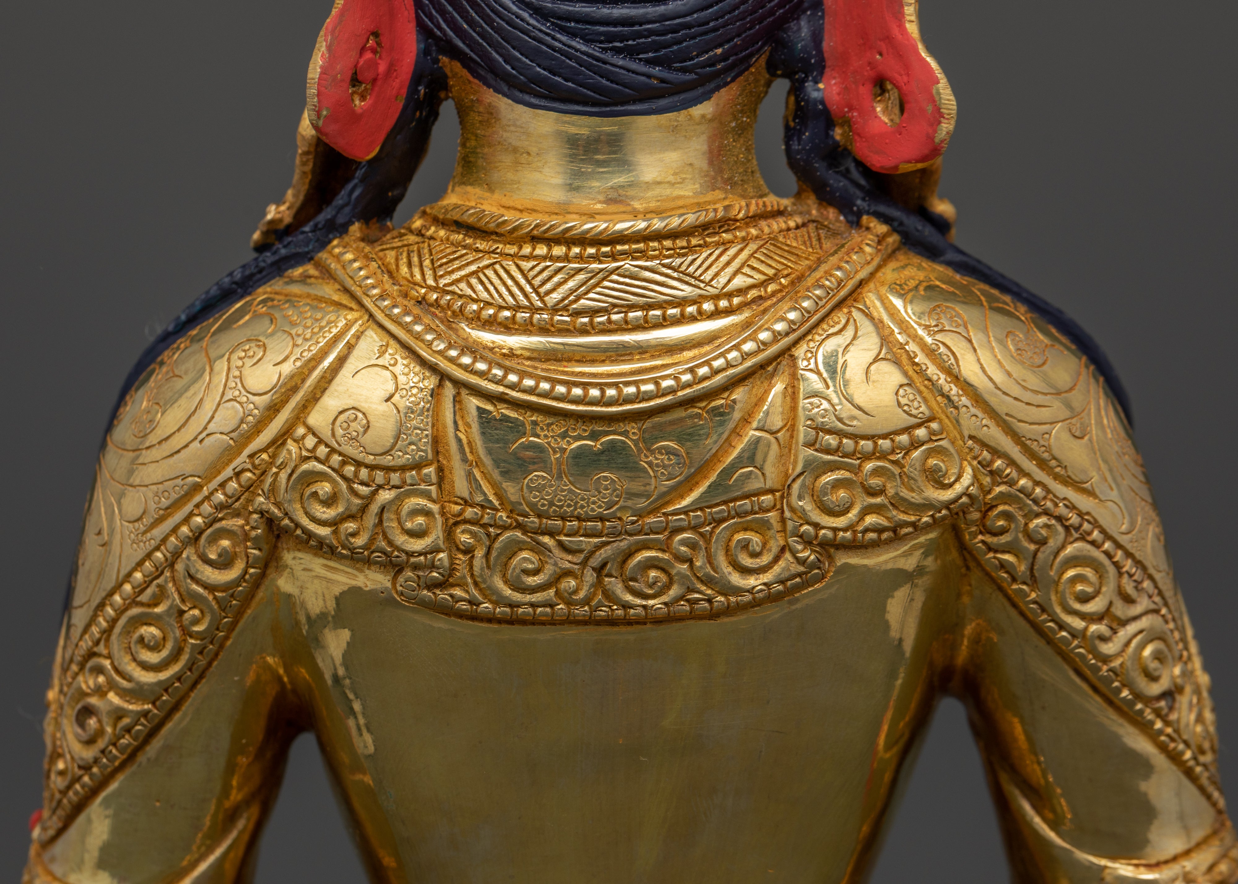 the shoulder part of gold plated Amitayus Hayagriva statue. Parts of acrylic colored black hair is seen
