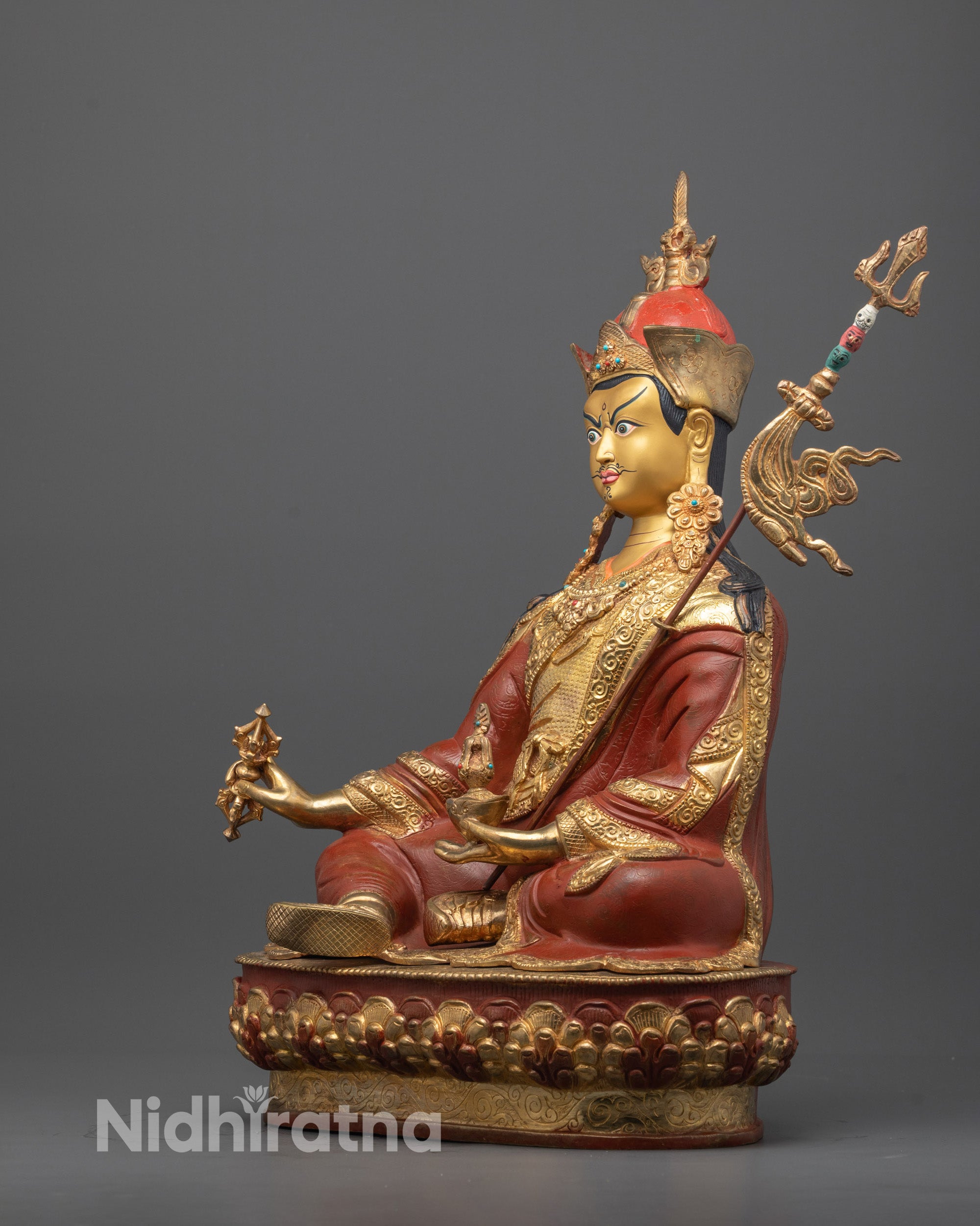 Angled shot of Guru Rinpoche holding vajra and skull cup with semi-precious stones