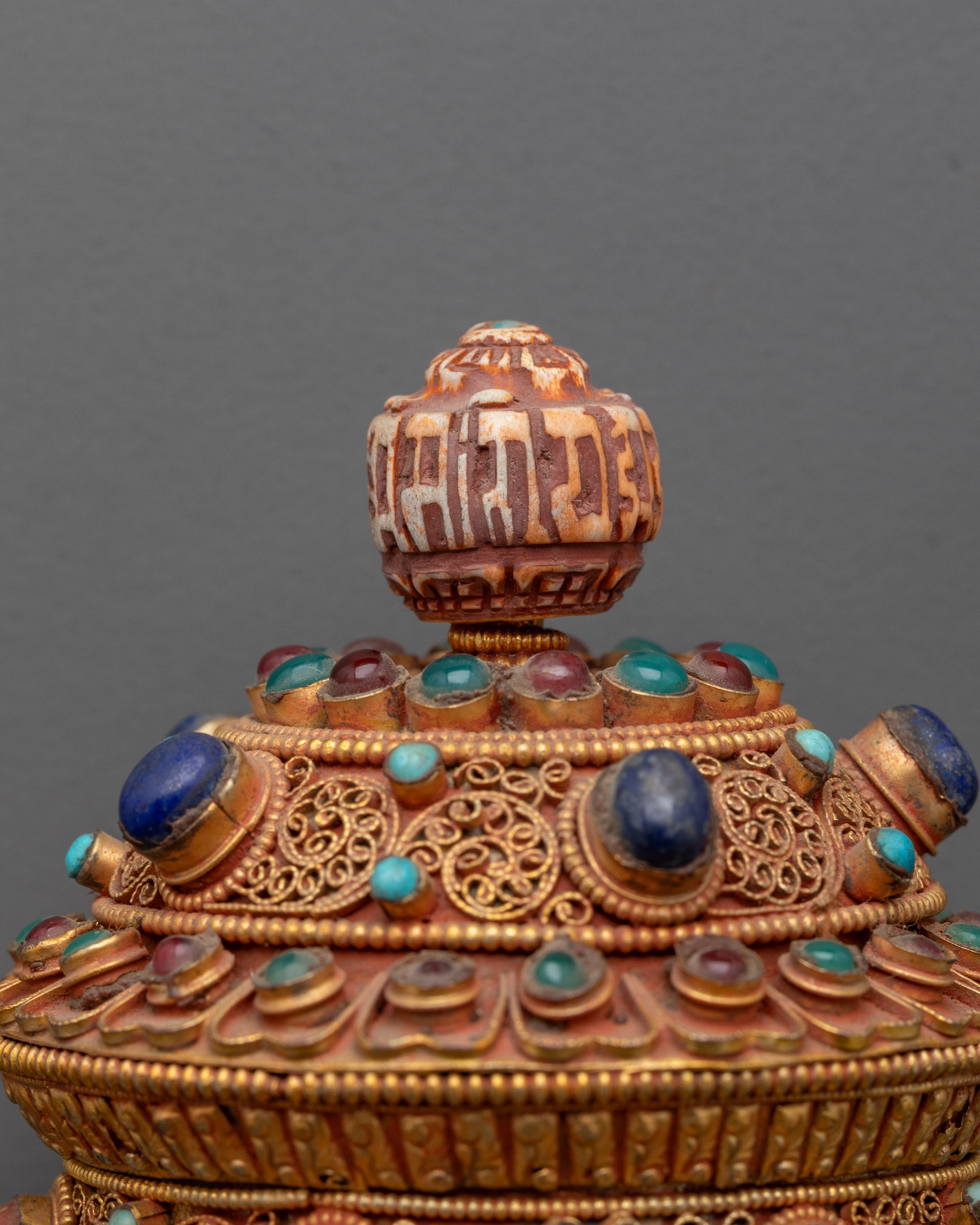 Angled view of copper and gold handheld mantra prayer wheel for meditation and spiritual practice