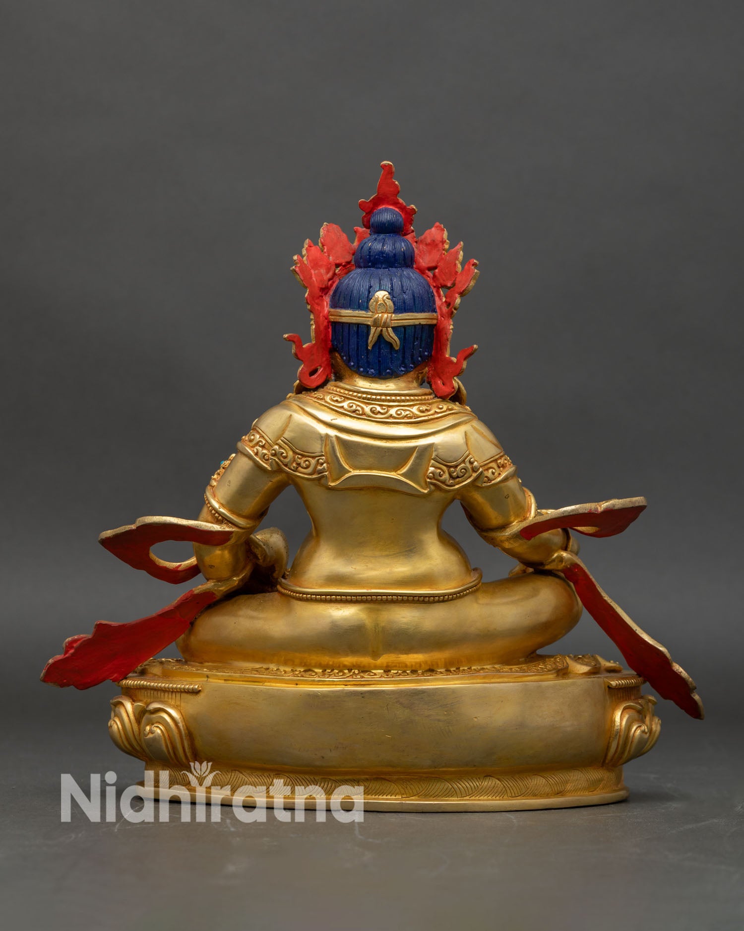 Back view of Dzambhala statue, showing carved lotus pedestal and ornate relief patterns