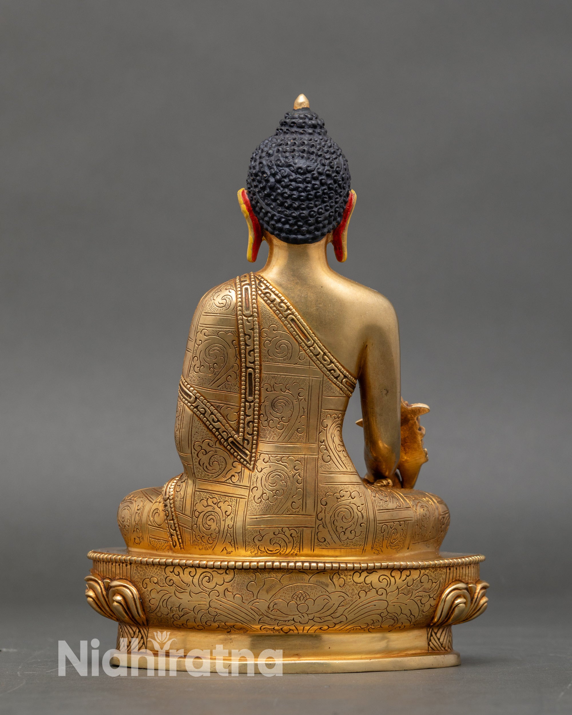 Back view of Medicine Buddha statue showing engraved lotus throne and traditional patterns