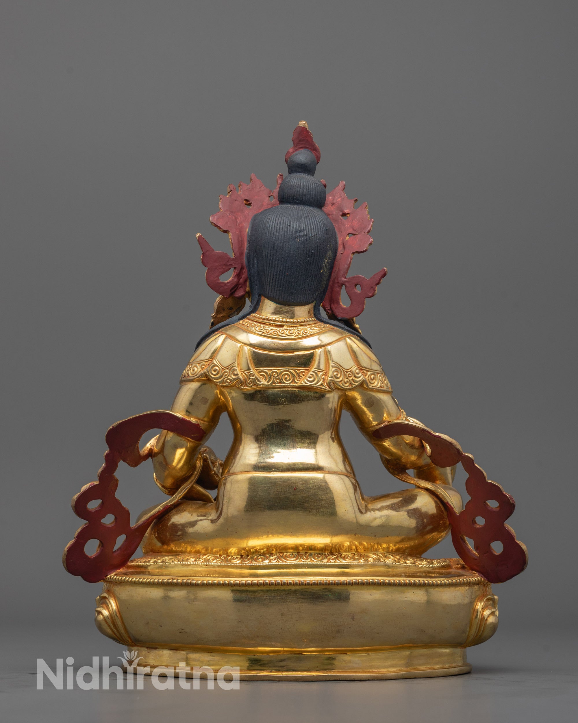 Back-view of Dzambhala Statue placed on altar setting with spiritual elements