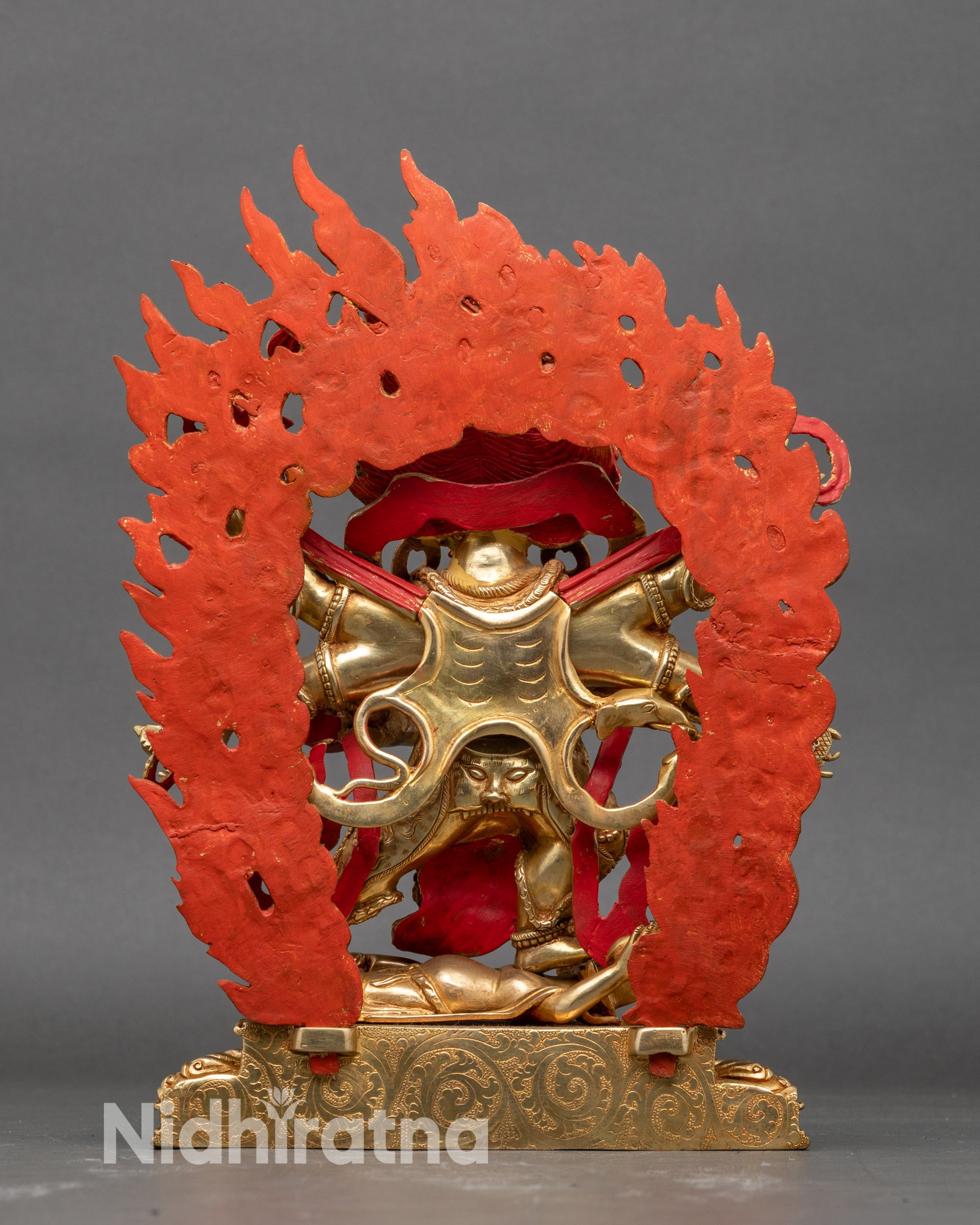 Back of Mahakala statue, lotus base, halo, and detailed robe carvings visible