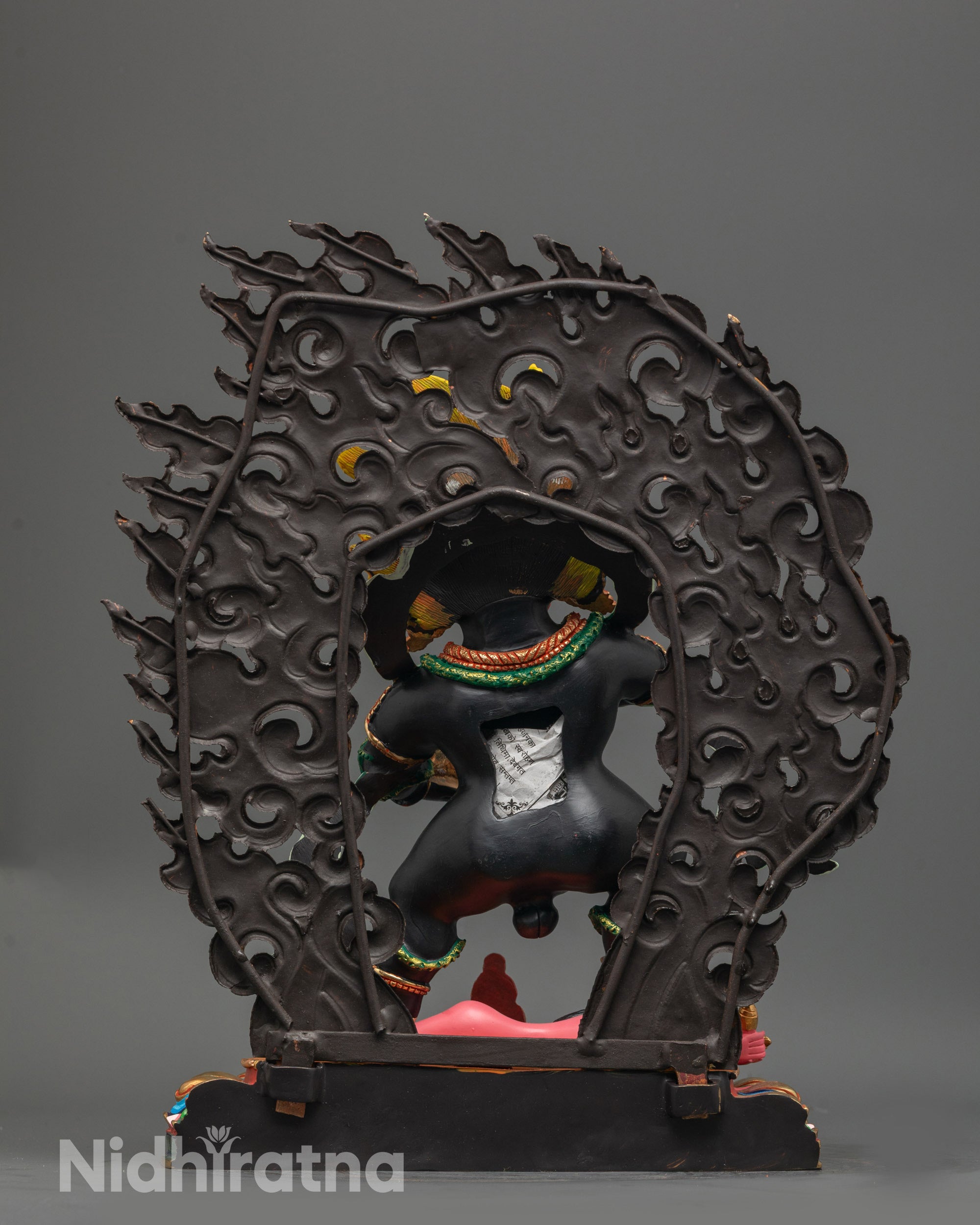 Back view Black Dzambhala statue showing wrathful halo and detailed multi colored seat