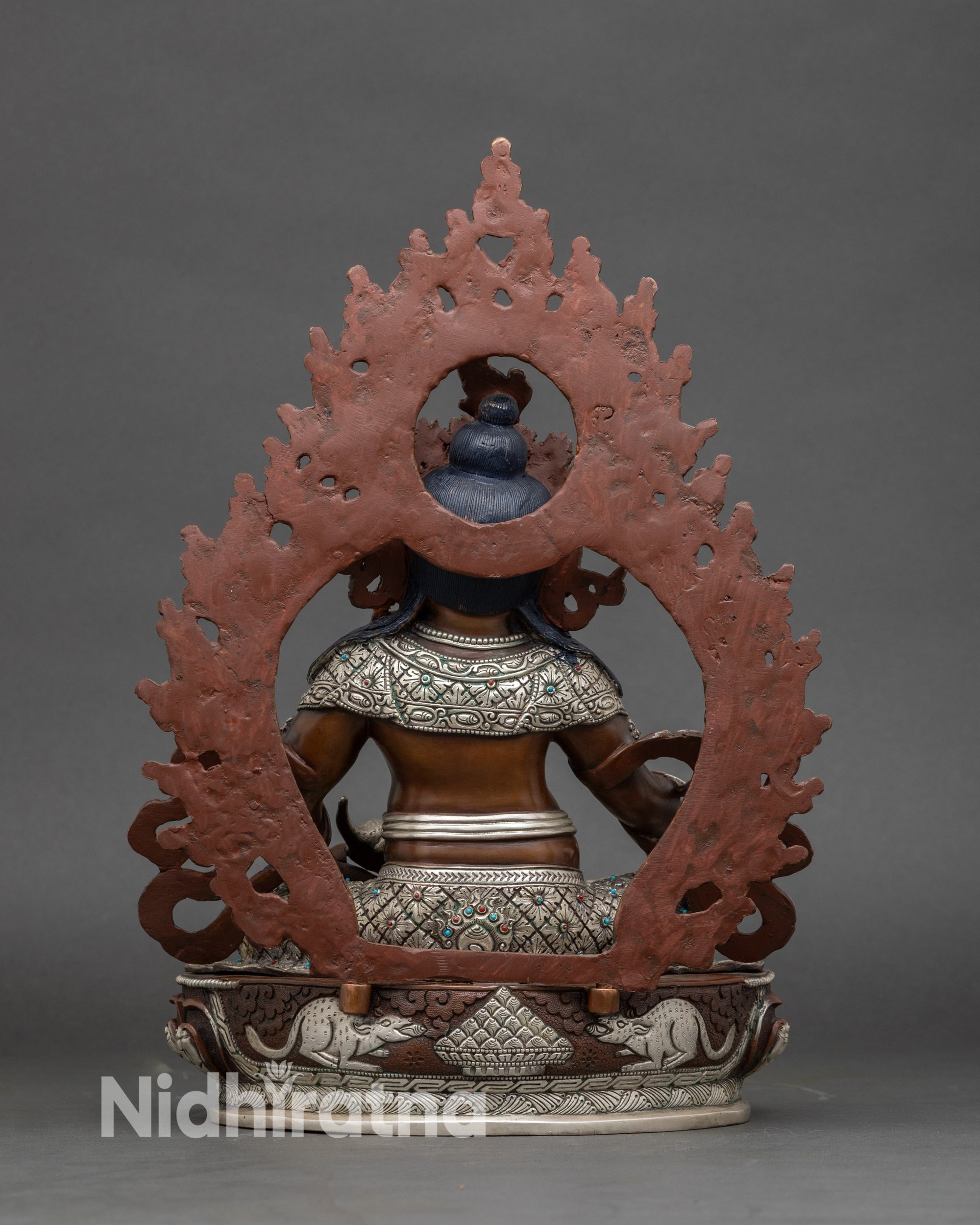 Back view Dzambhala statue with carved conch, twin mongoose and precious jewels on throne