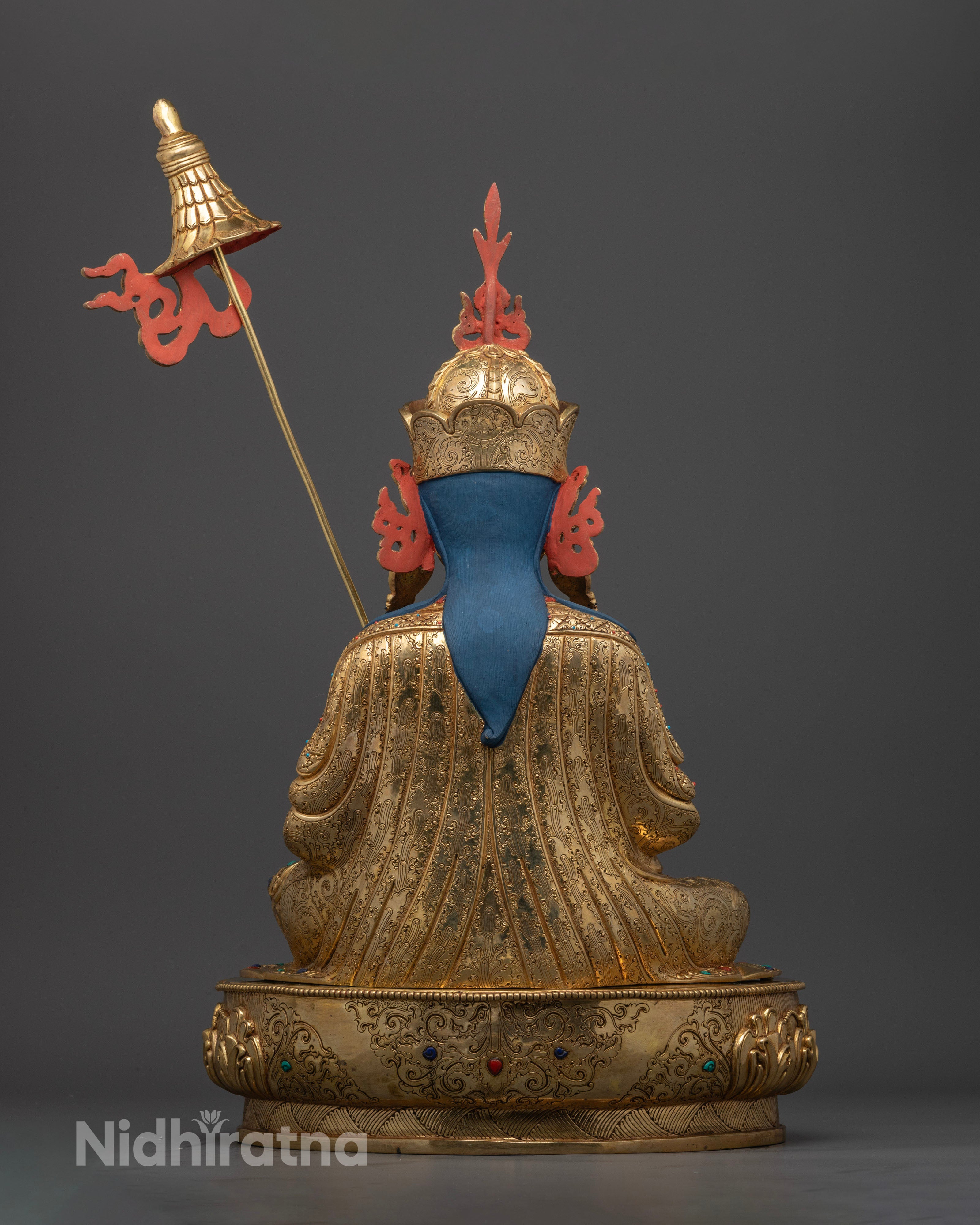 Back view Guru Norlha statue with intricately carved kasaya robes and lotus pedestal, traditional Himalayan Buddhist sculpture