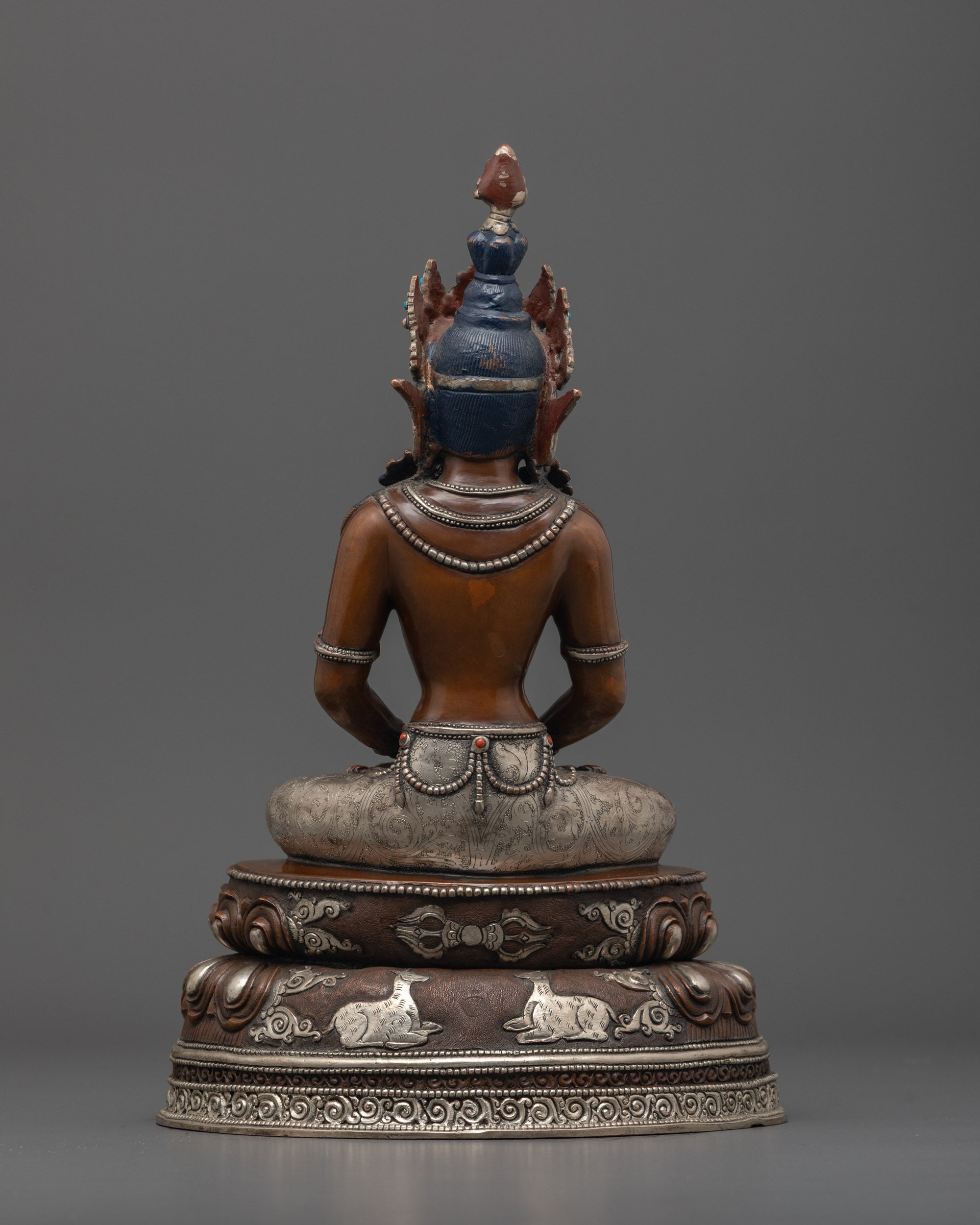 Back view of Amitayus statue highlighting silver-plated lower garments and intricate design