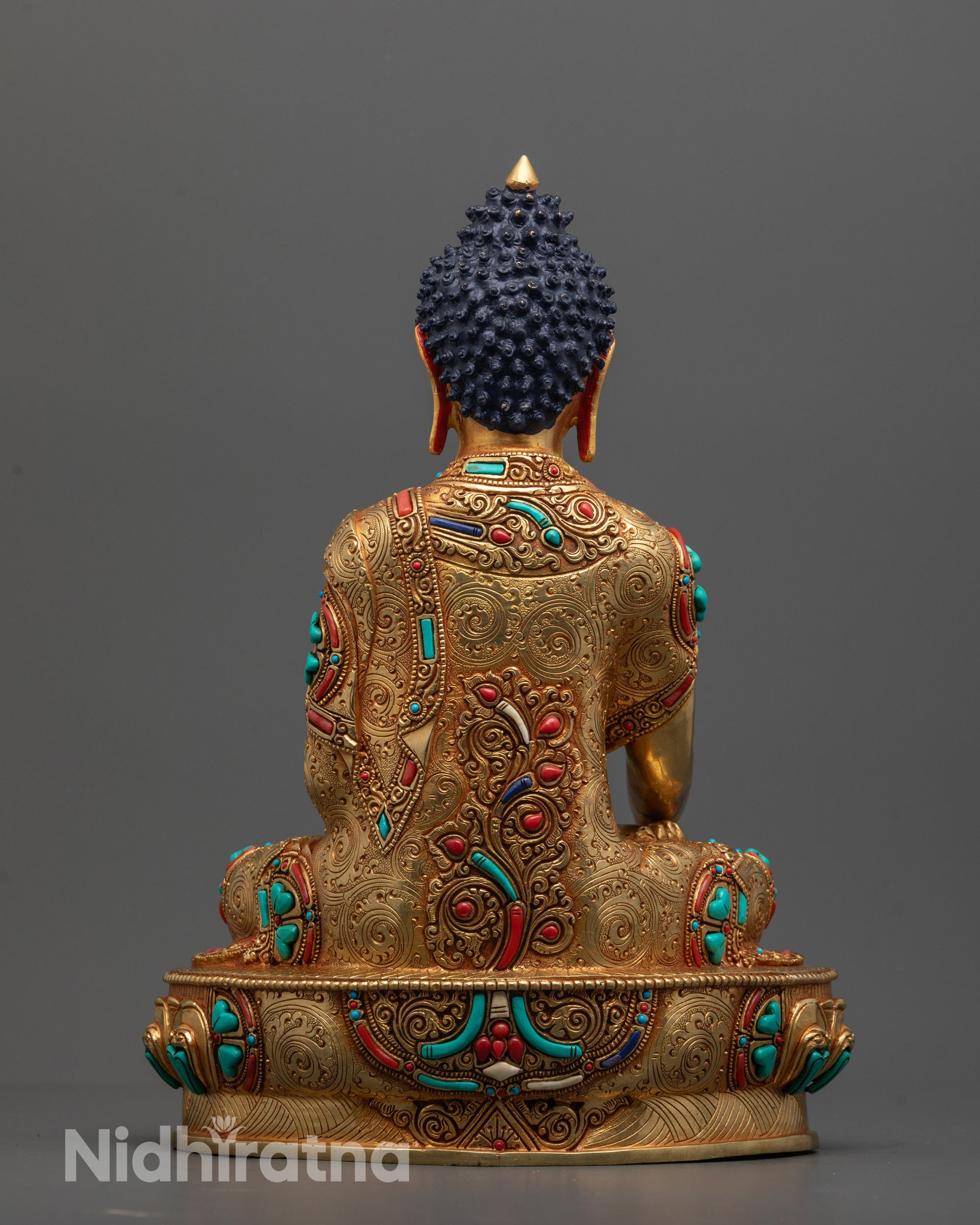 Back view of Buddha Shakyamuni statue showing intricate robe patterns and lotus seat