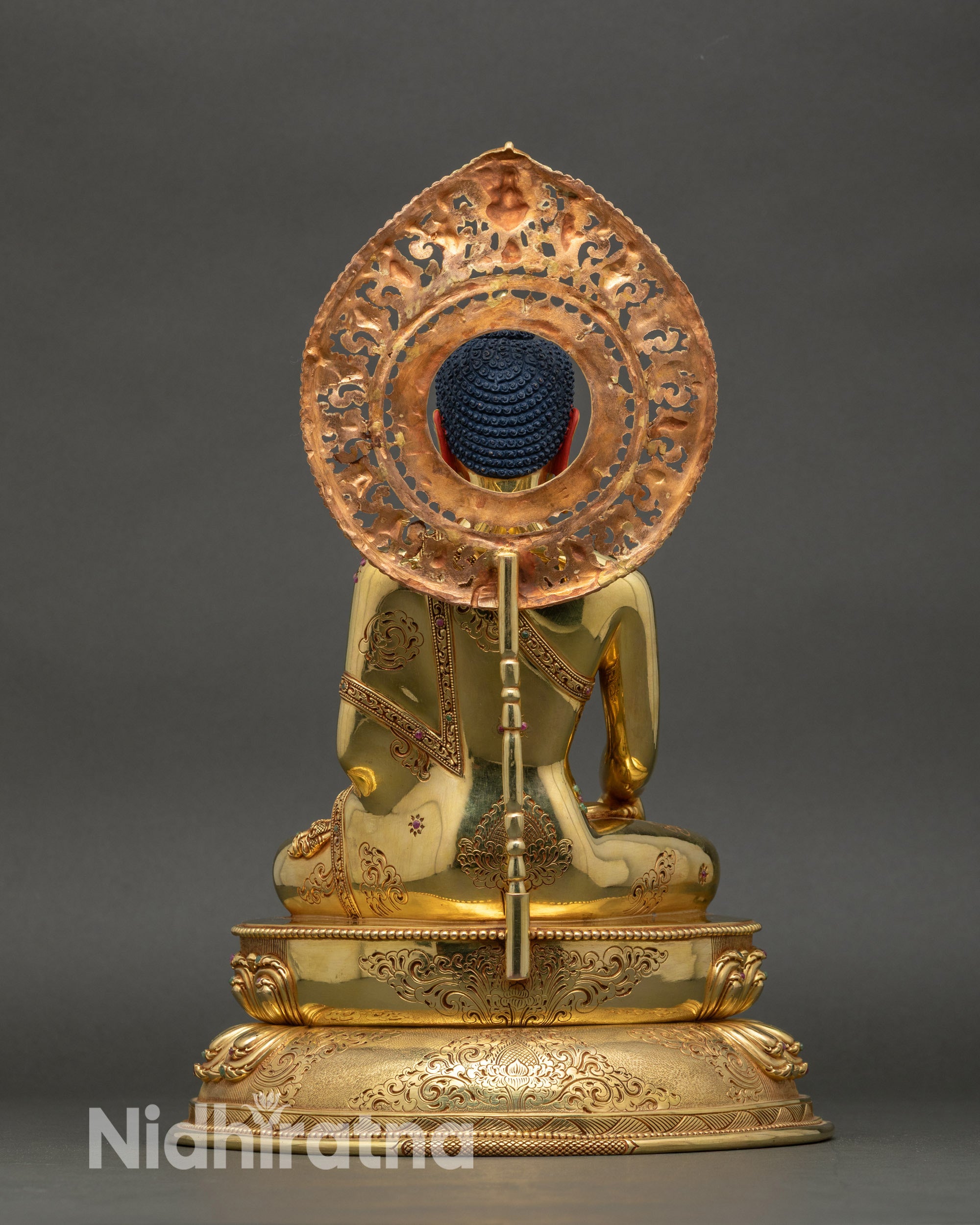 Back view of Buddha statue, engraved lotus base and ornate copper details