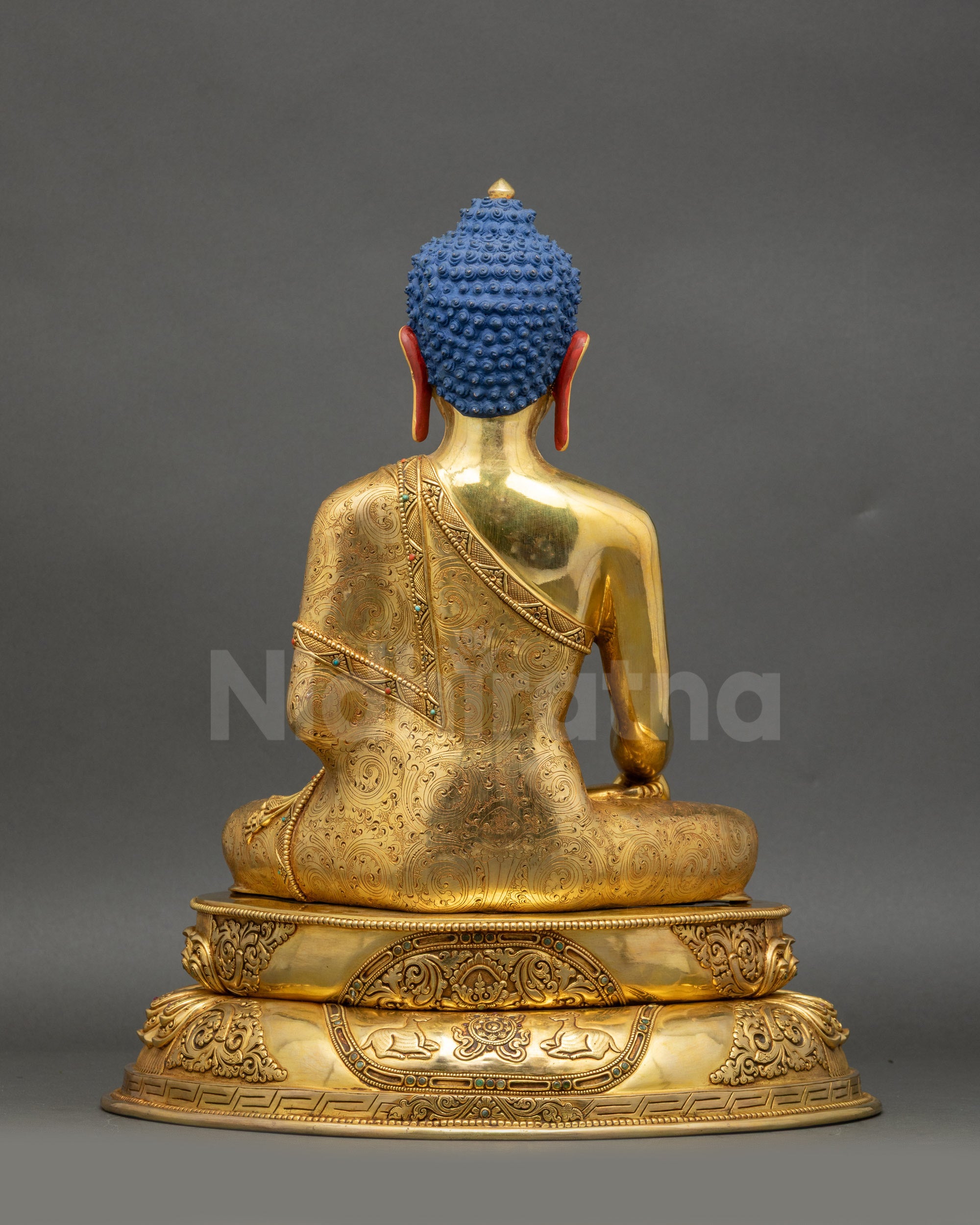 Back view of Buddha statue showing Wisdom Wheel and pair of Deer on pedestal