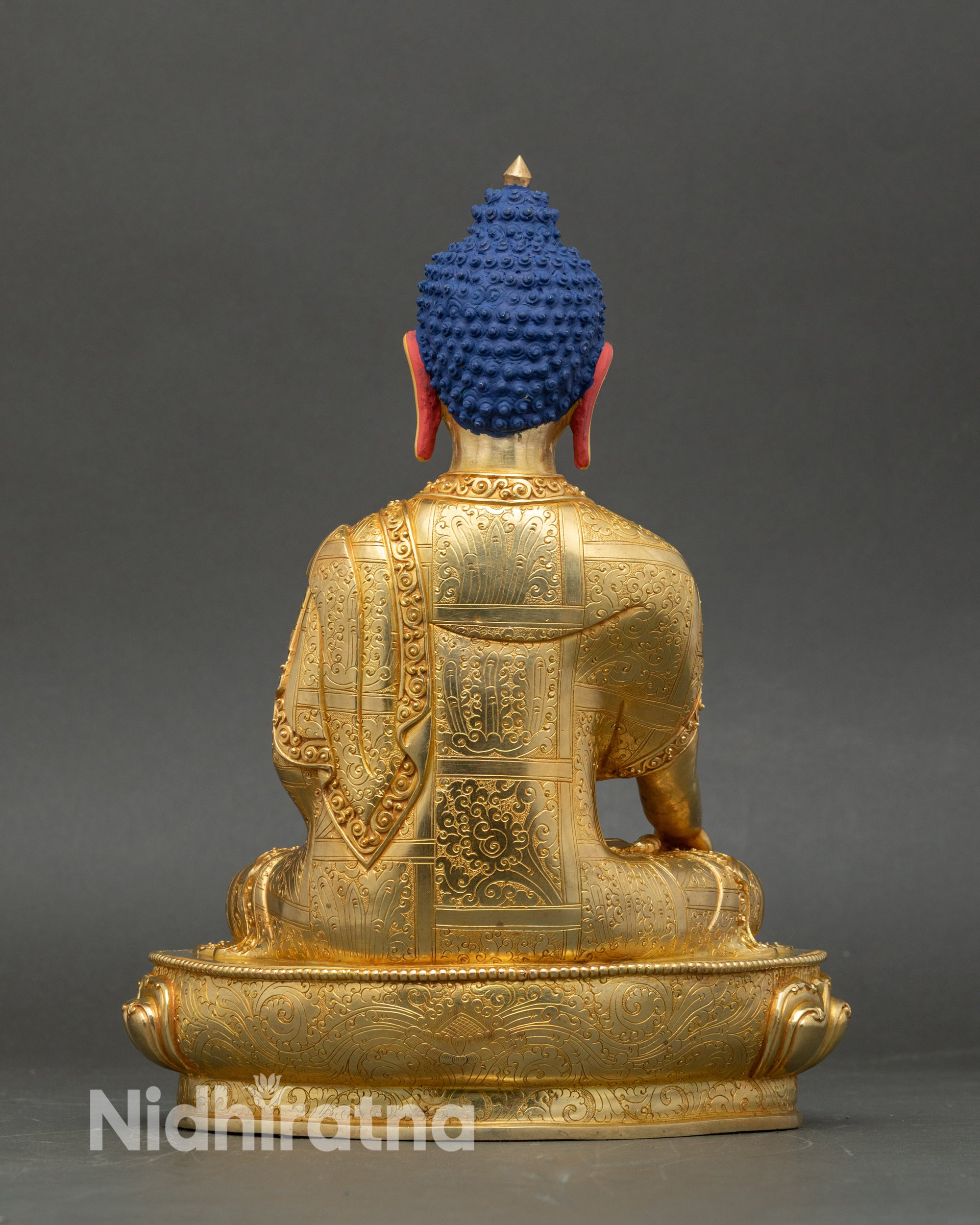 Back view of Buddha statue showing intricate 3D carvings and radiant fire-gilded layers