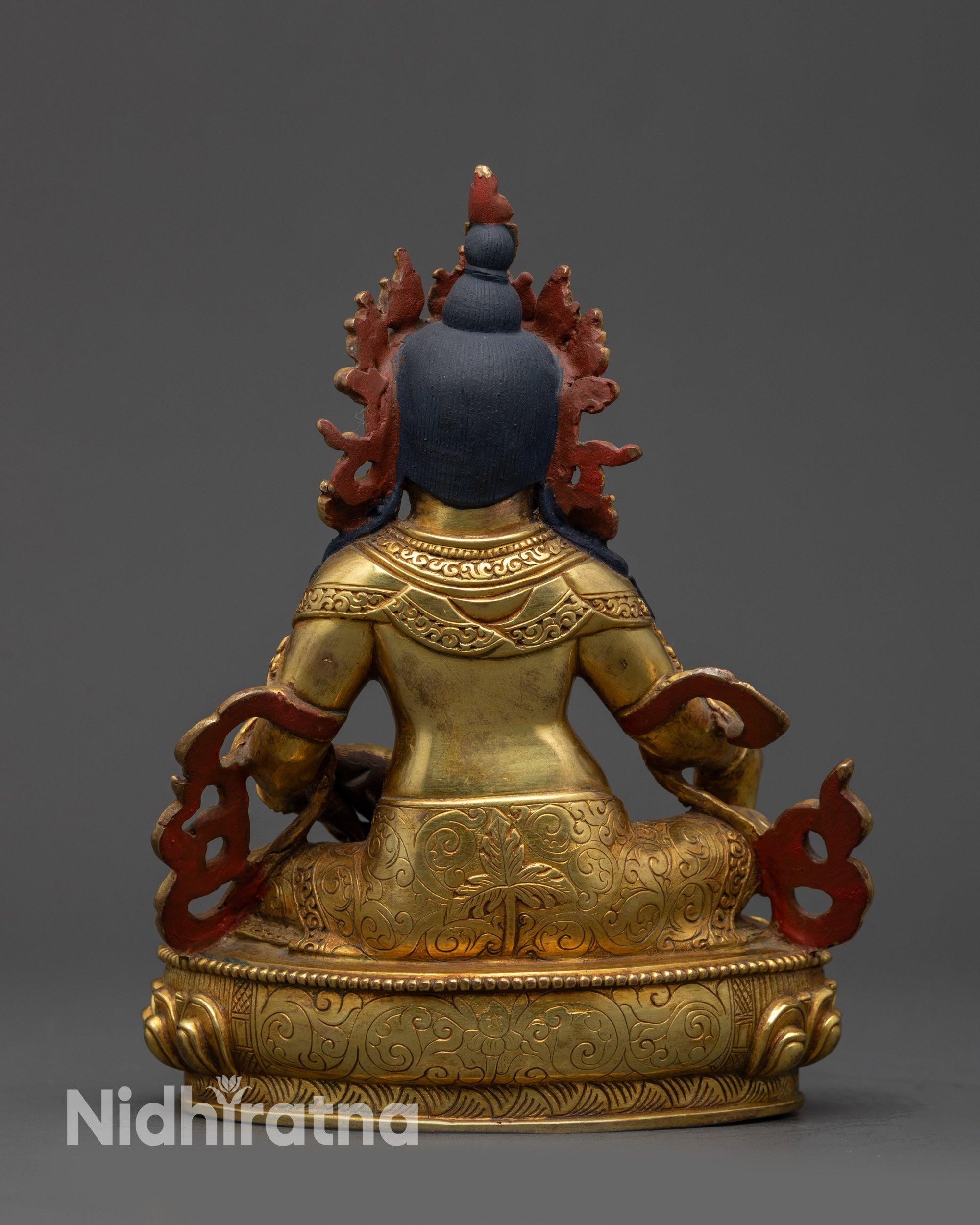 Back view of Dzambhala Statue showing detailed carved garments and radiant glow