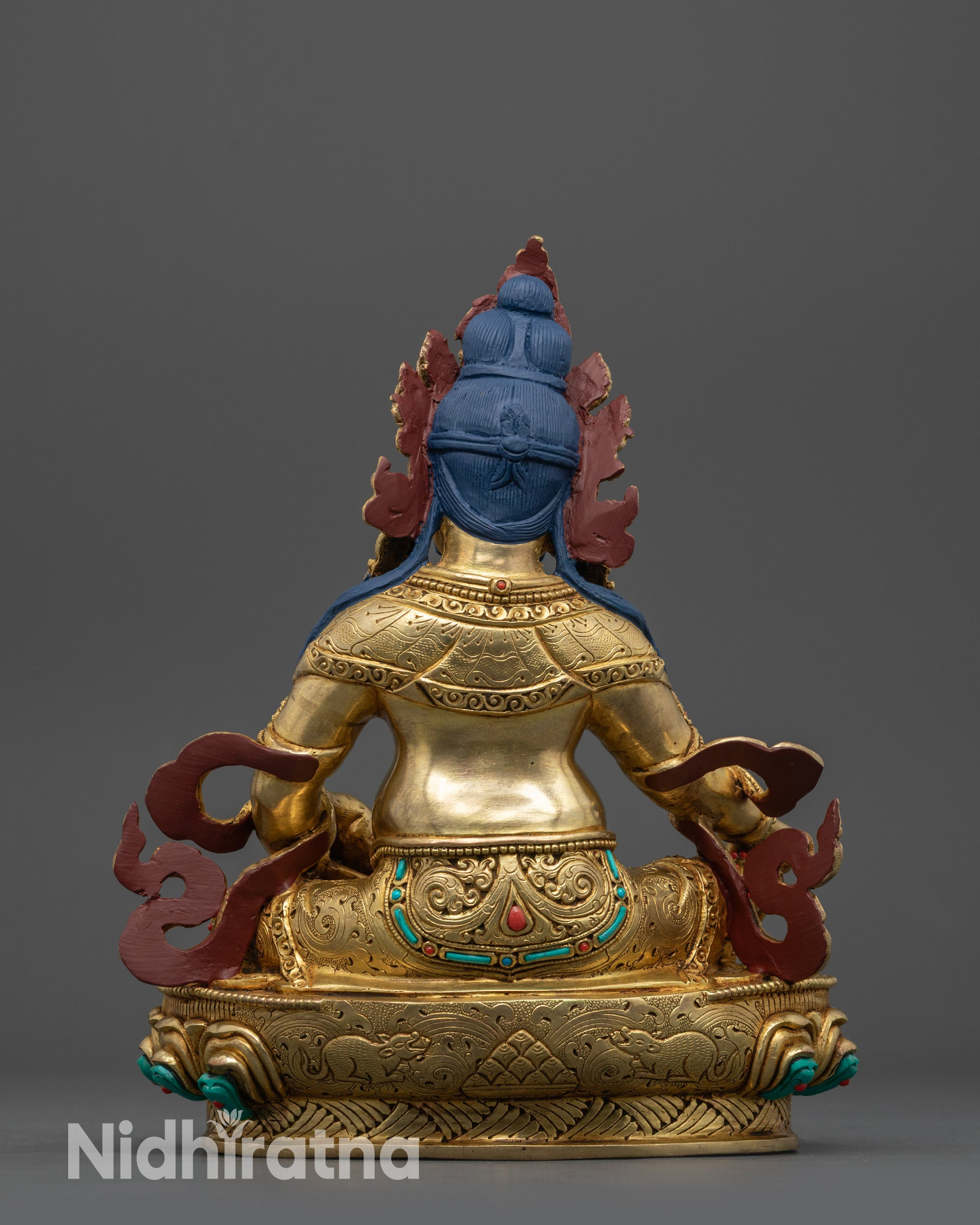 Back view of Dzambhala statue displaying serpent, detailed garment carvings, and polished finish
