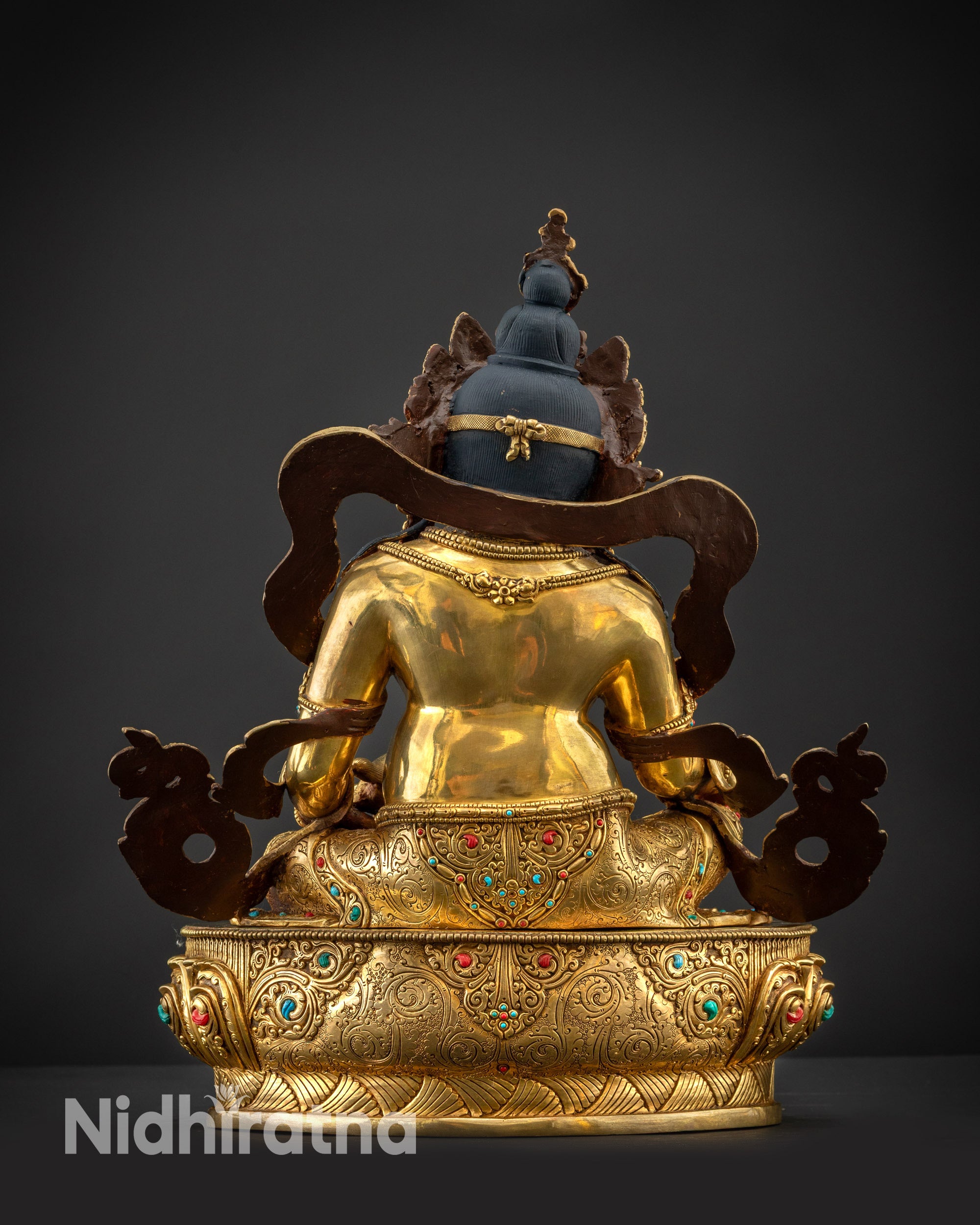 Back view of Dzambhala statue showing carved lower garments and lotus pedestal