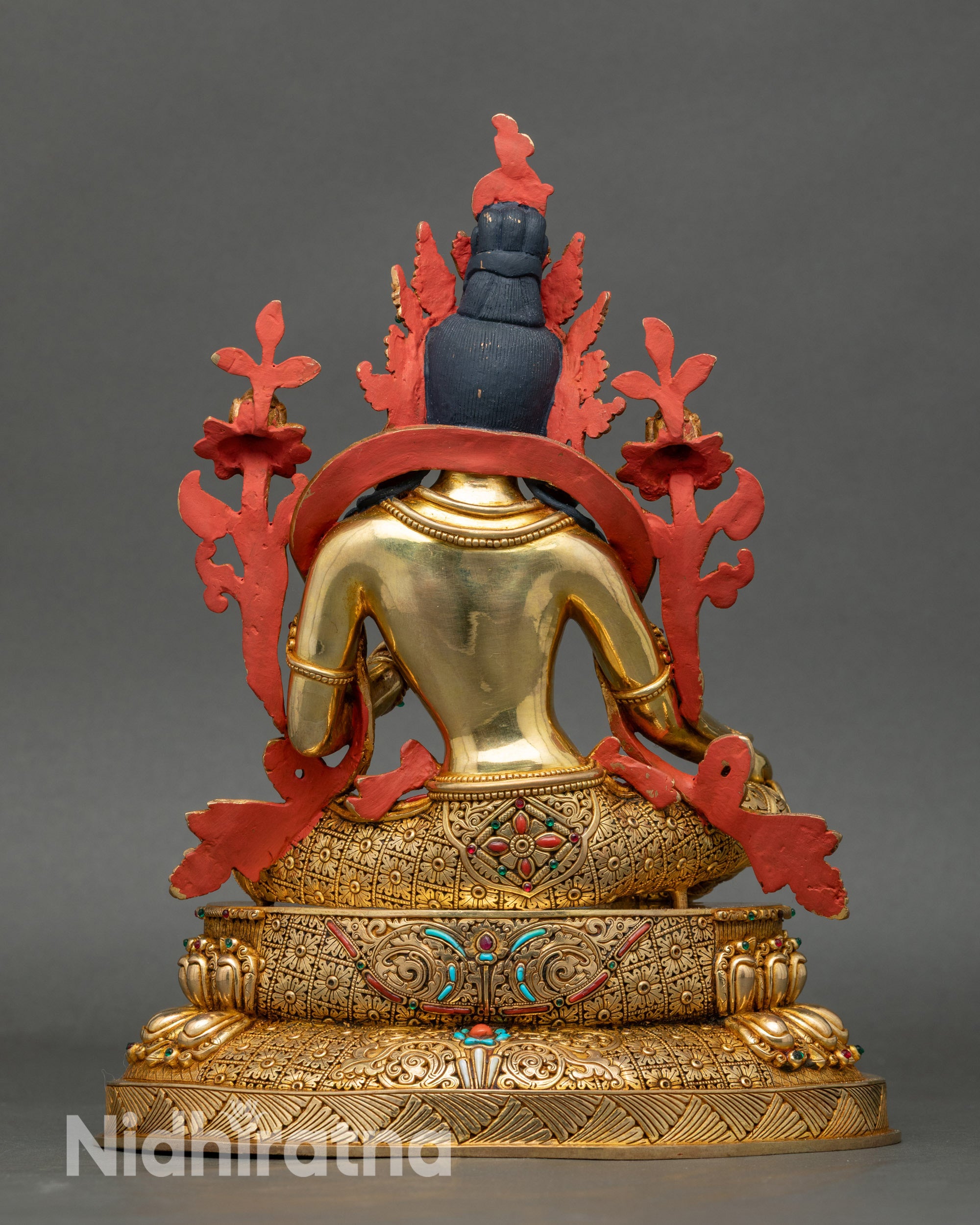 Back view of Green Tara statue highlighting flowing carved robes and halo