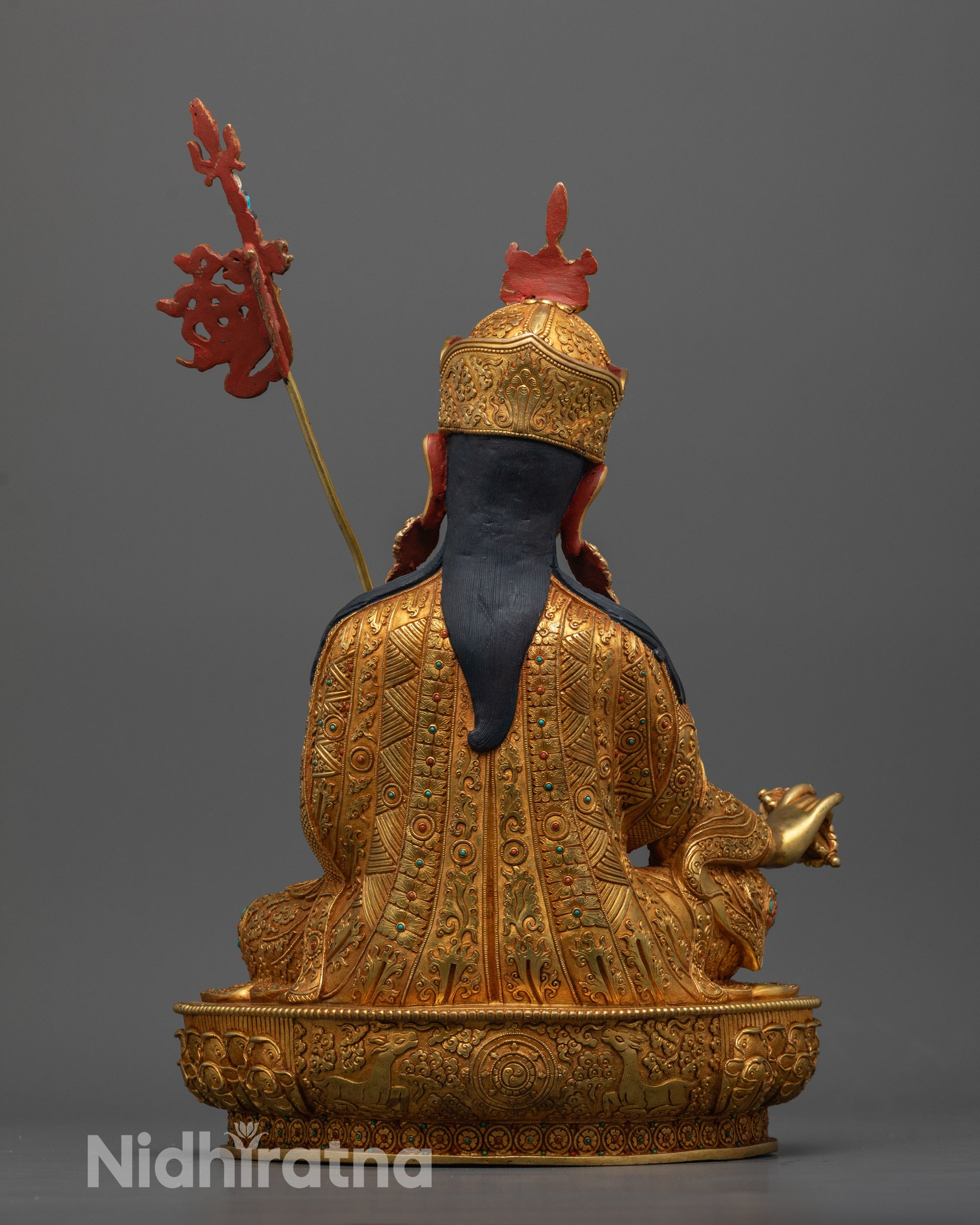 Back view of Guru Rinpoche statue showing dharma wheel and deer on lotus base