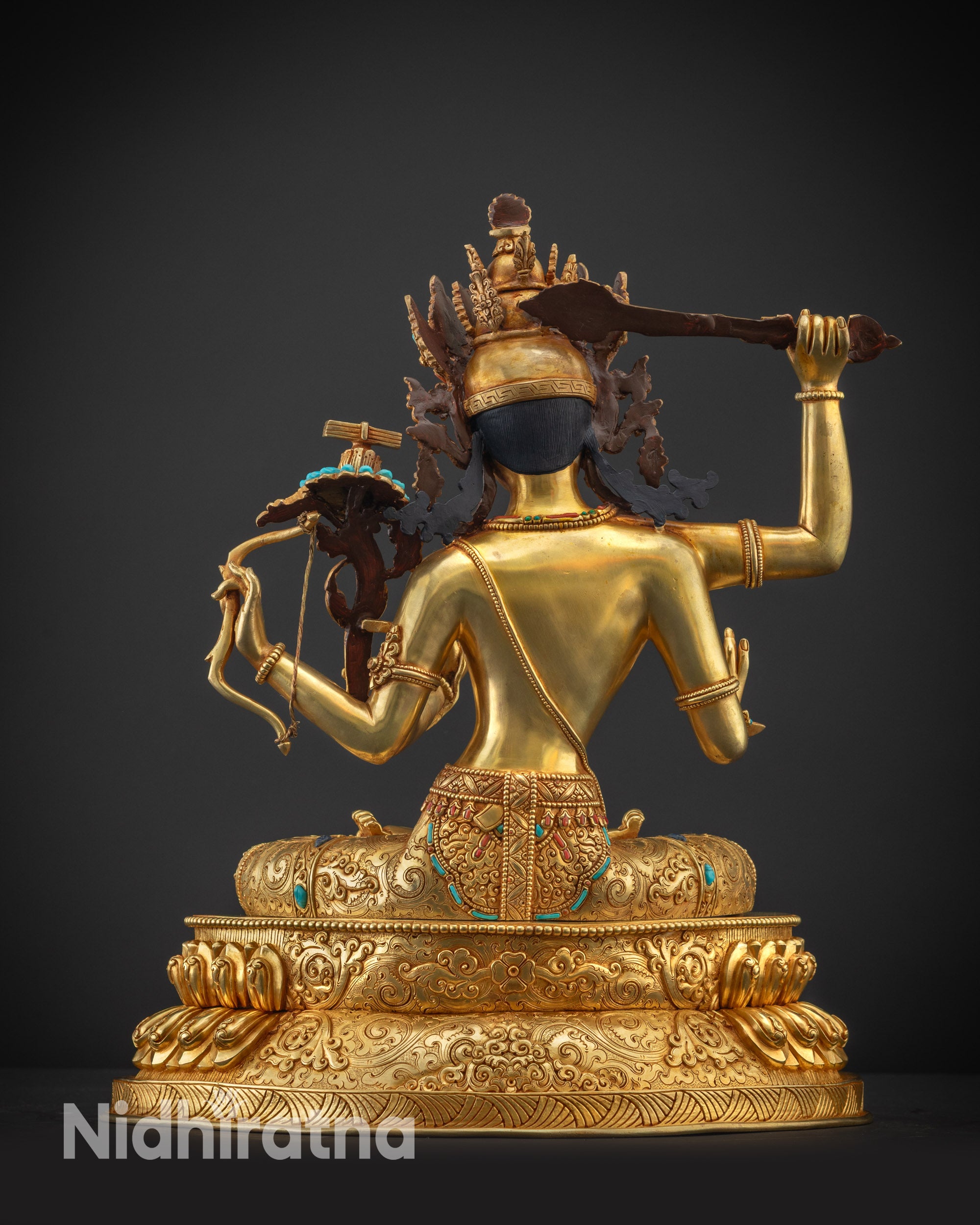 Back view of Maha Manjushri statue revealing detailed robe and polished golden lotus base surface.