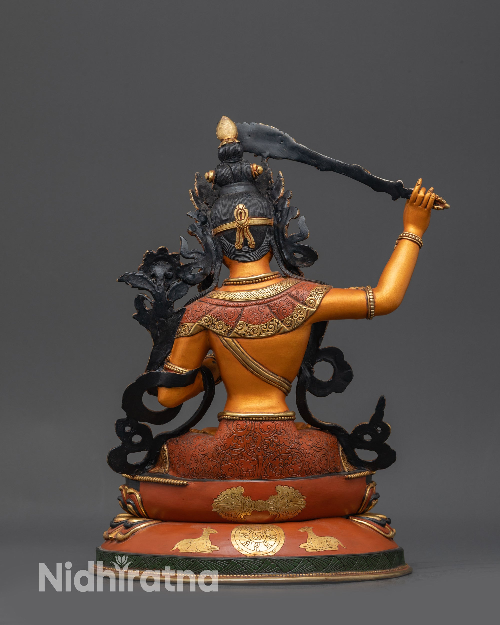 Back view of Manjushri Statue showing double-layered lotus base with dharma wheel and deer