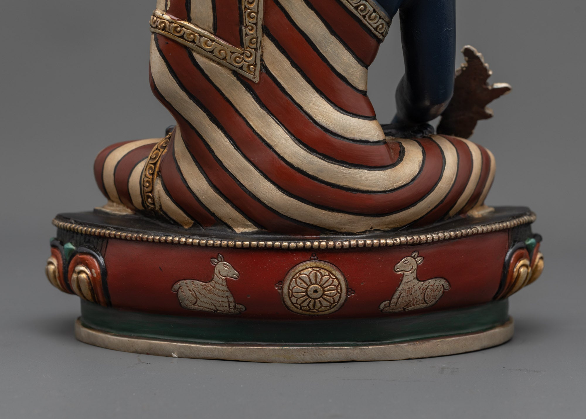Back view of Medicine Buddha showing detailed lotus seat and carved dharma wheel symbols.