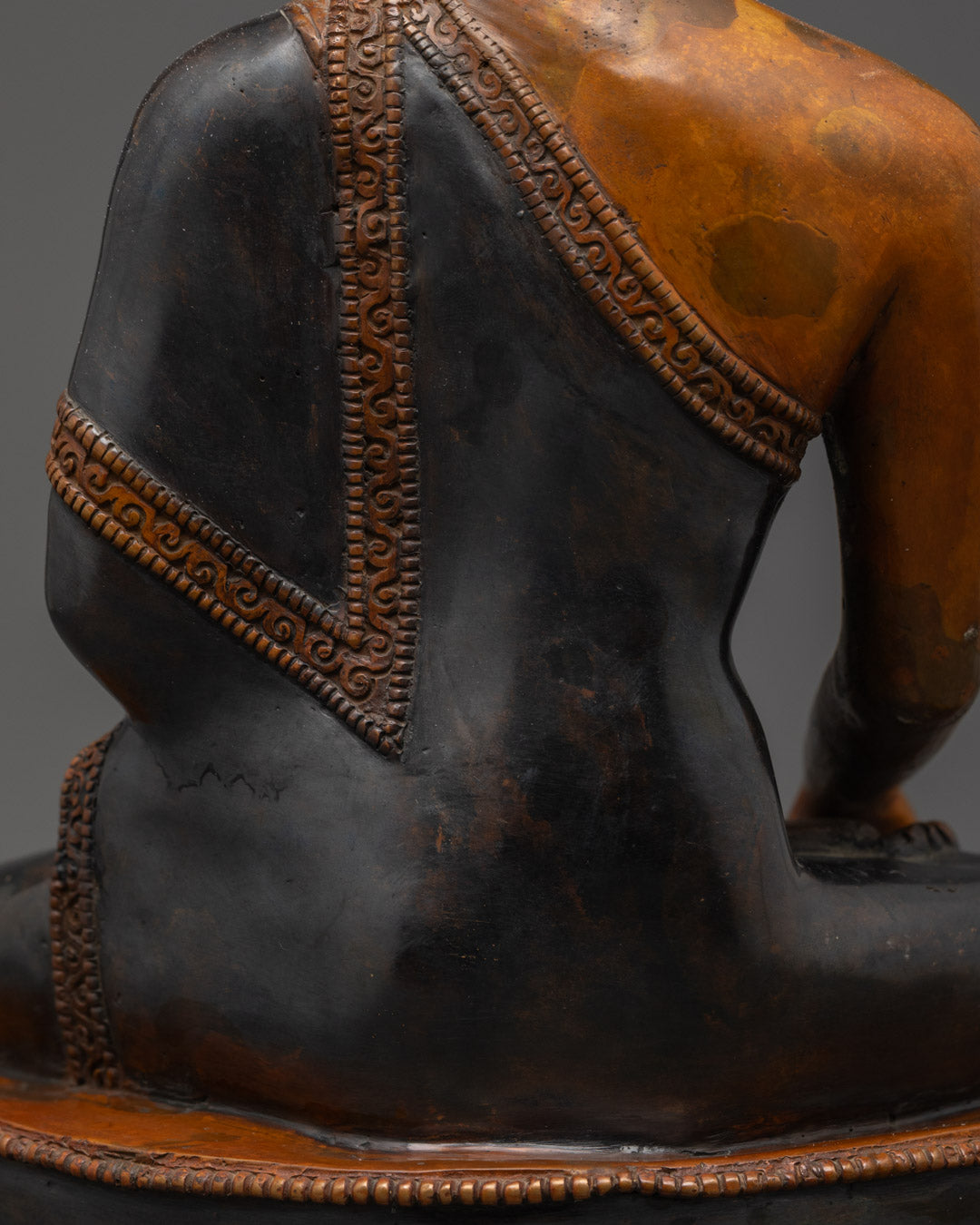 Back view of Shakyamuni Buddha statue highlighting oxidized copper texture and artisan craft