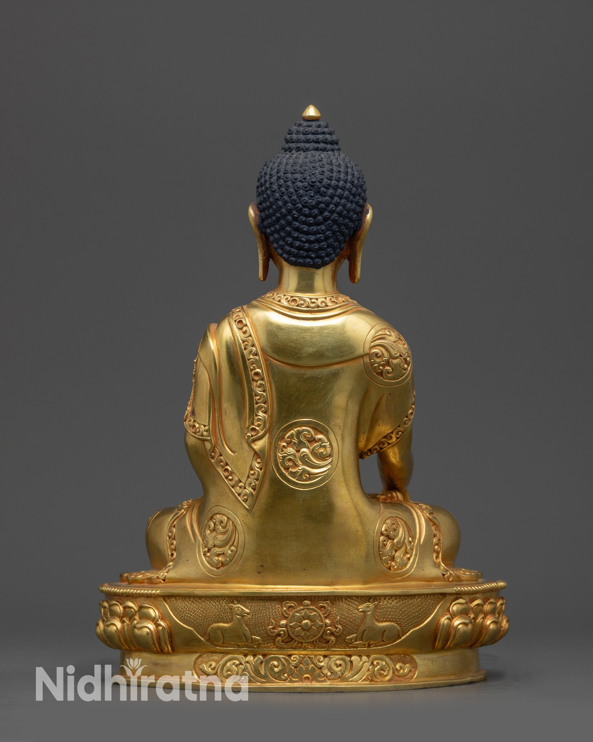 Back view of gold fire-gilded Shakyamuni Buddha statue showing detailed monk’s robe patterns.