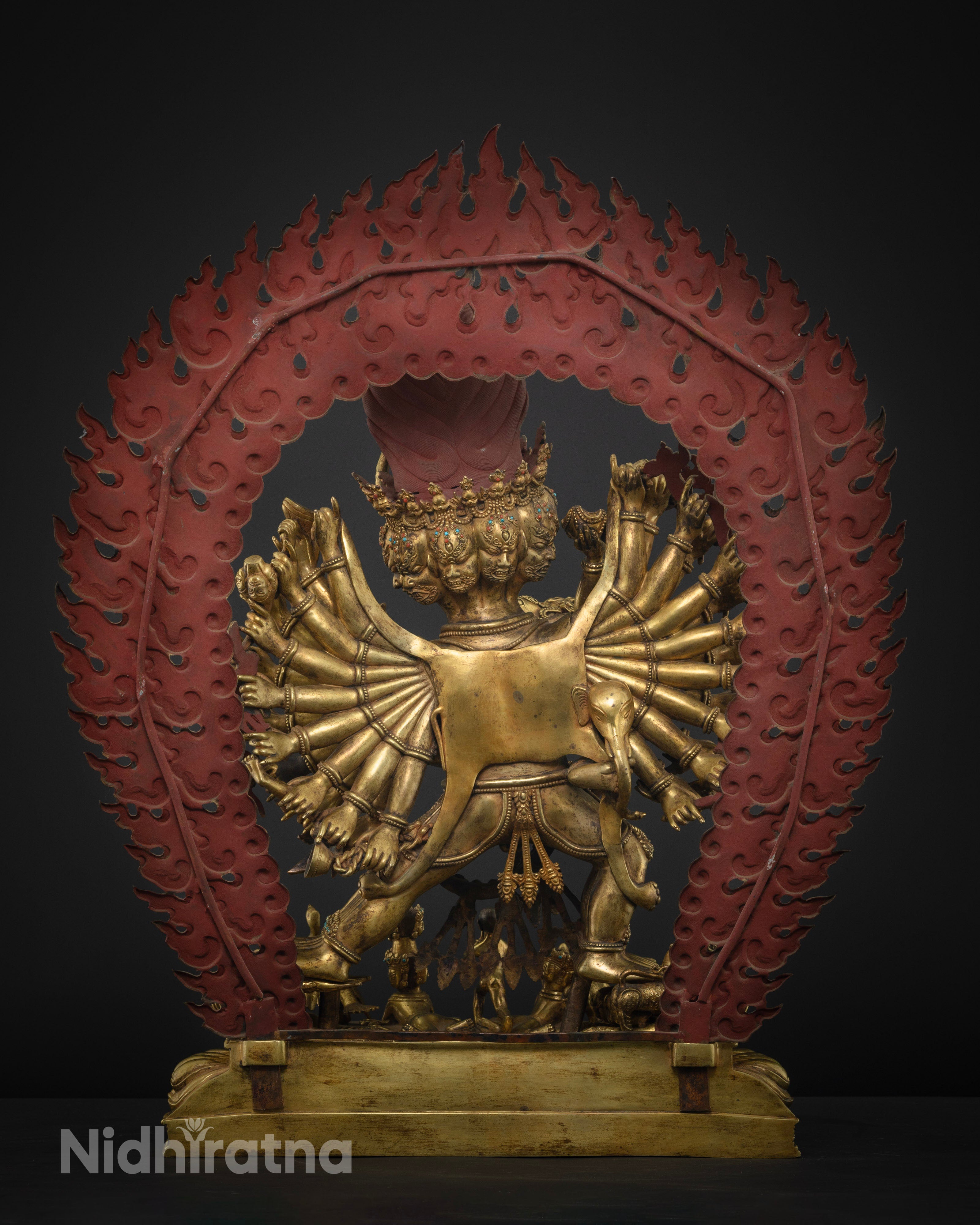 Back view of intricate fire carvings on blazing halo and hand-carved miniature deities on base