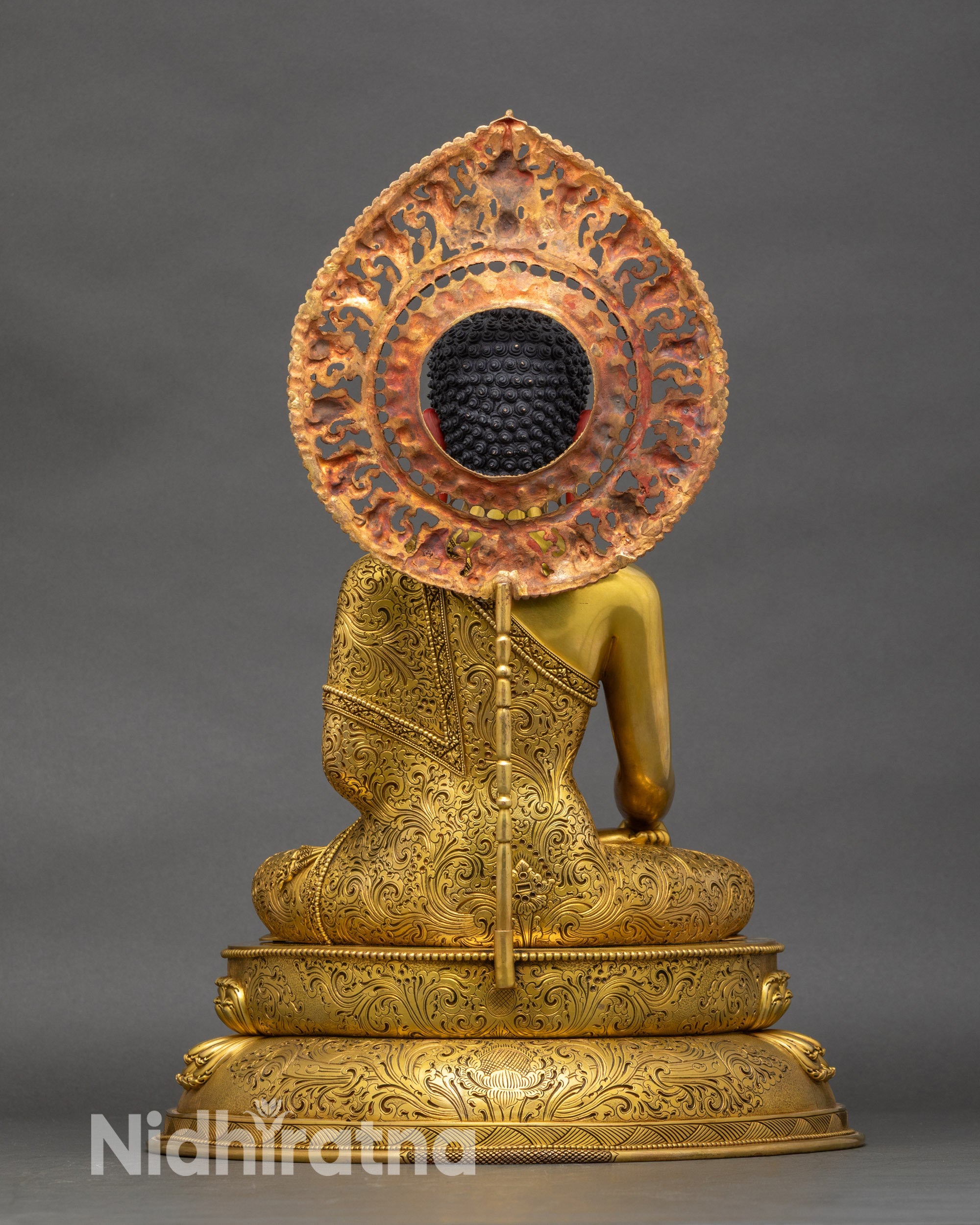 Back view of life-size Buddha statue showing flowing robes and lotus seat