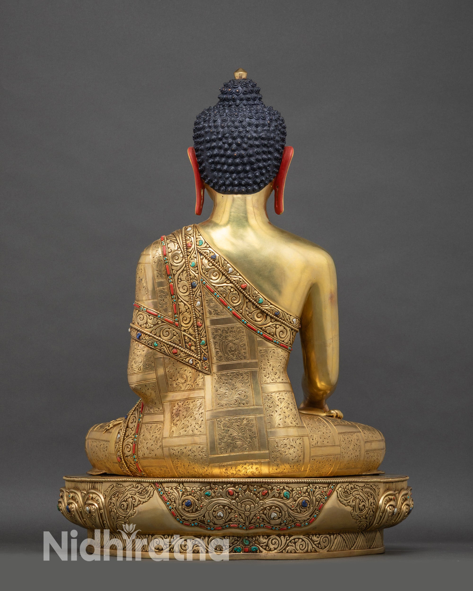 Back view of life-size Shakyamuni Buddha statue, showing detailed carvings and golden finish