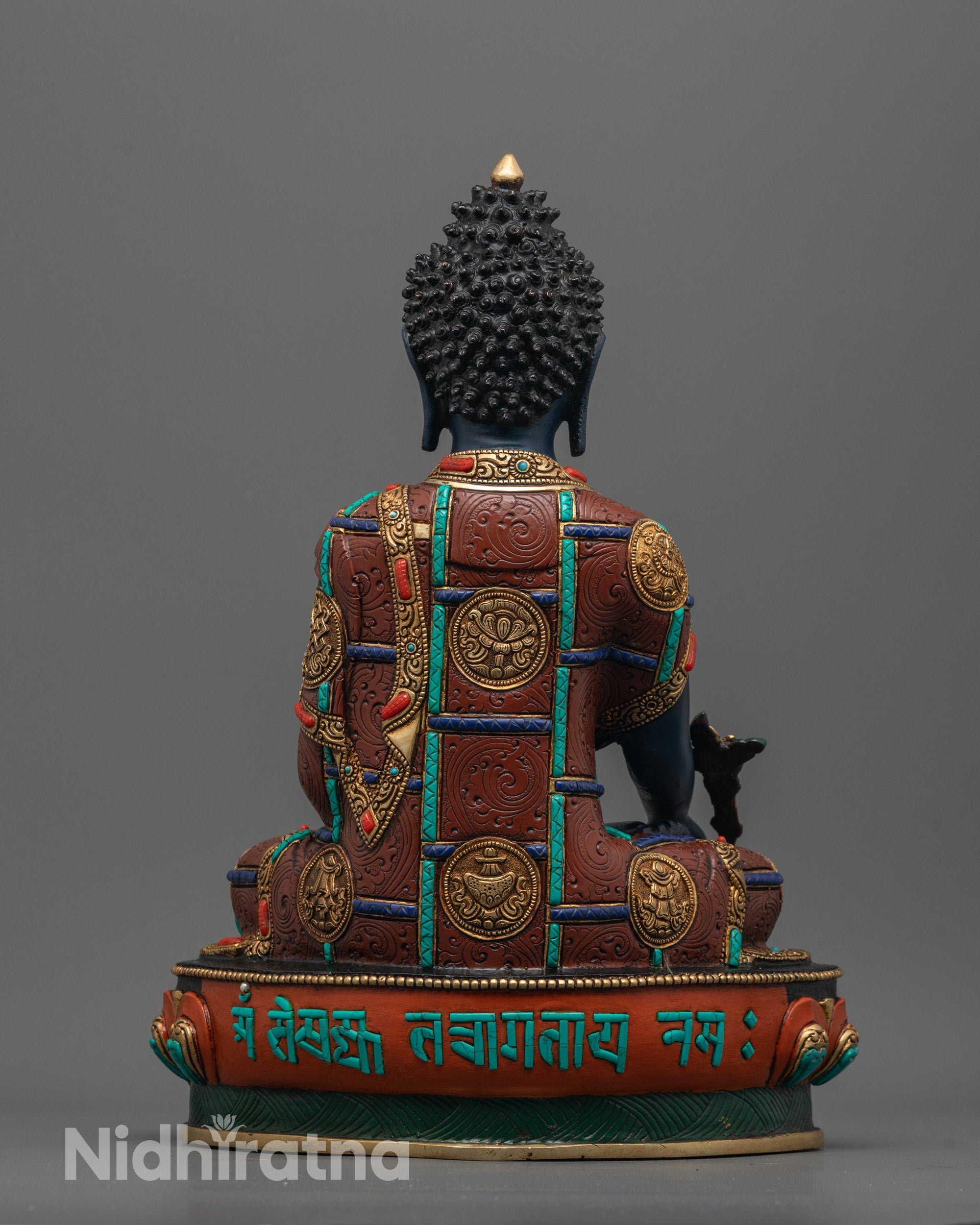 Back view showing engraved sacred mantra and ashtamangala symbols on Medicine Buddha lotus seat