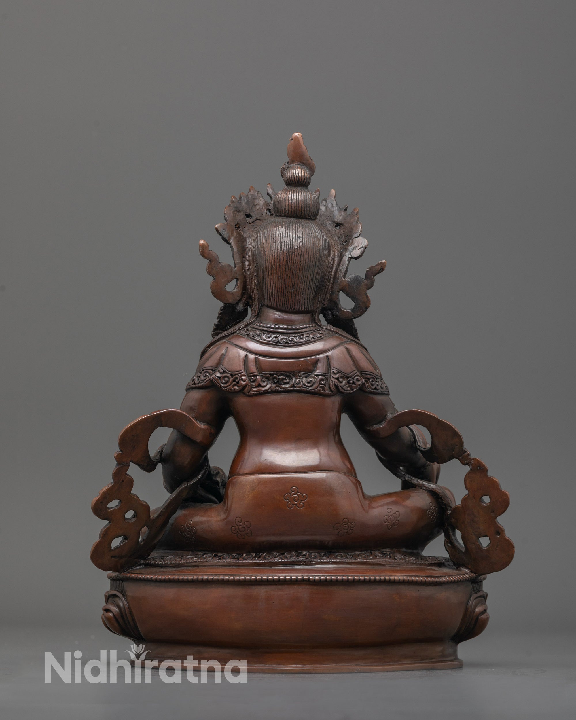 Back view showing flowing robes and unique patterns carved on oxidized Dzambhala statue