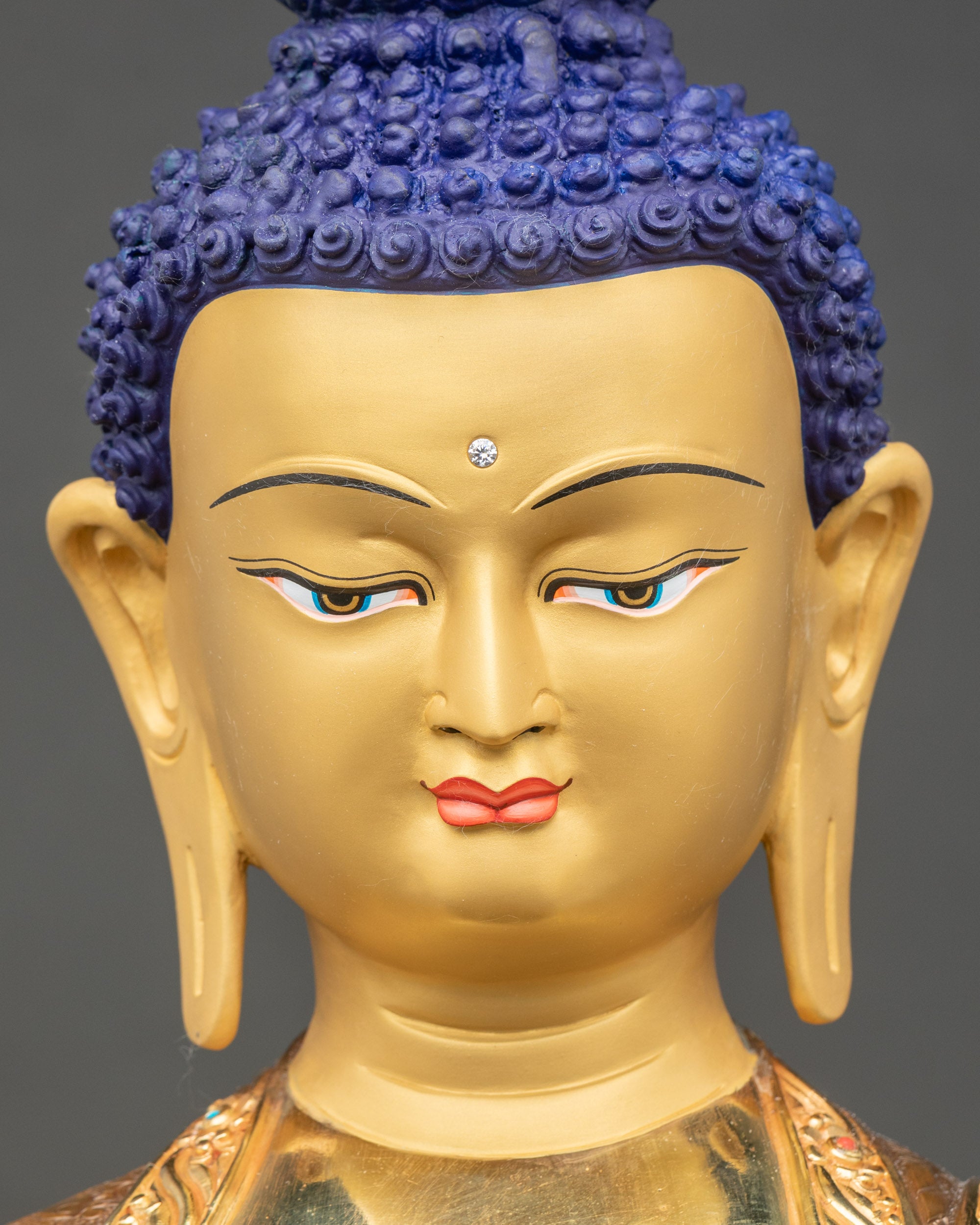 Detailed close-up of Buddha face with gold paint, Himalayan artisan sculpture