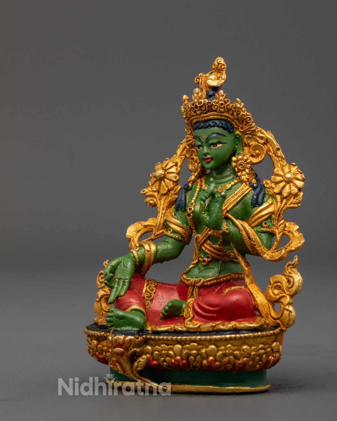 Buddhist Green Tara statue holding uptala flower and displaying granting mudra seated on lotus throne with green halo for meditation