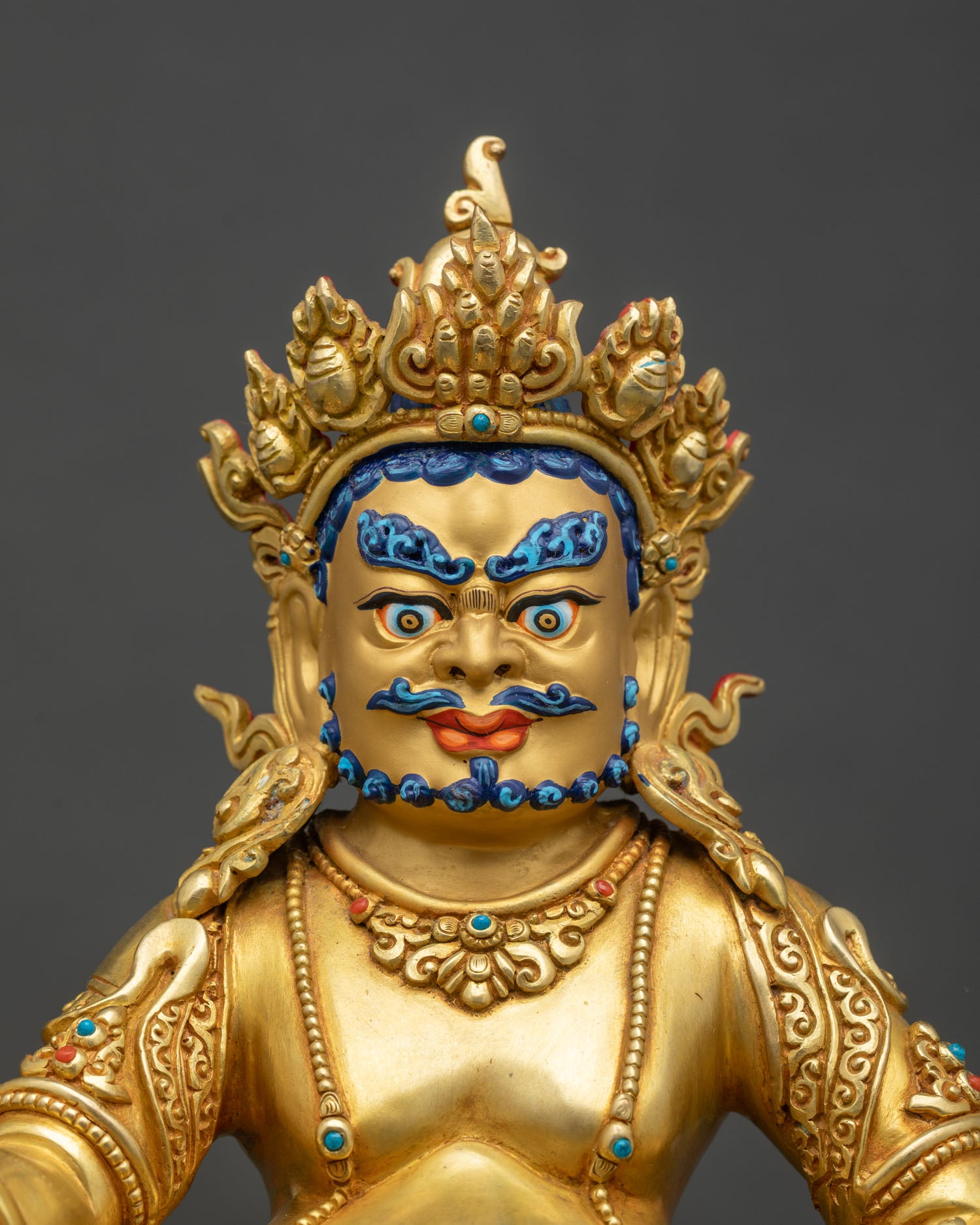 Close-up of Dzambhala statue showing detailed copper and gold relief carvings