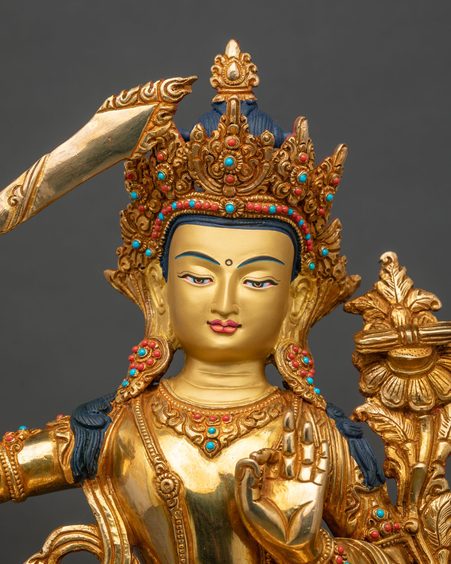 Close up Manjushri statue gold-painted face semi-precious stones intricate details