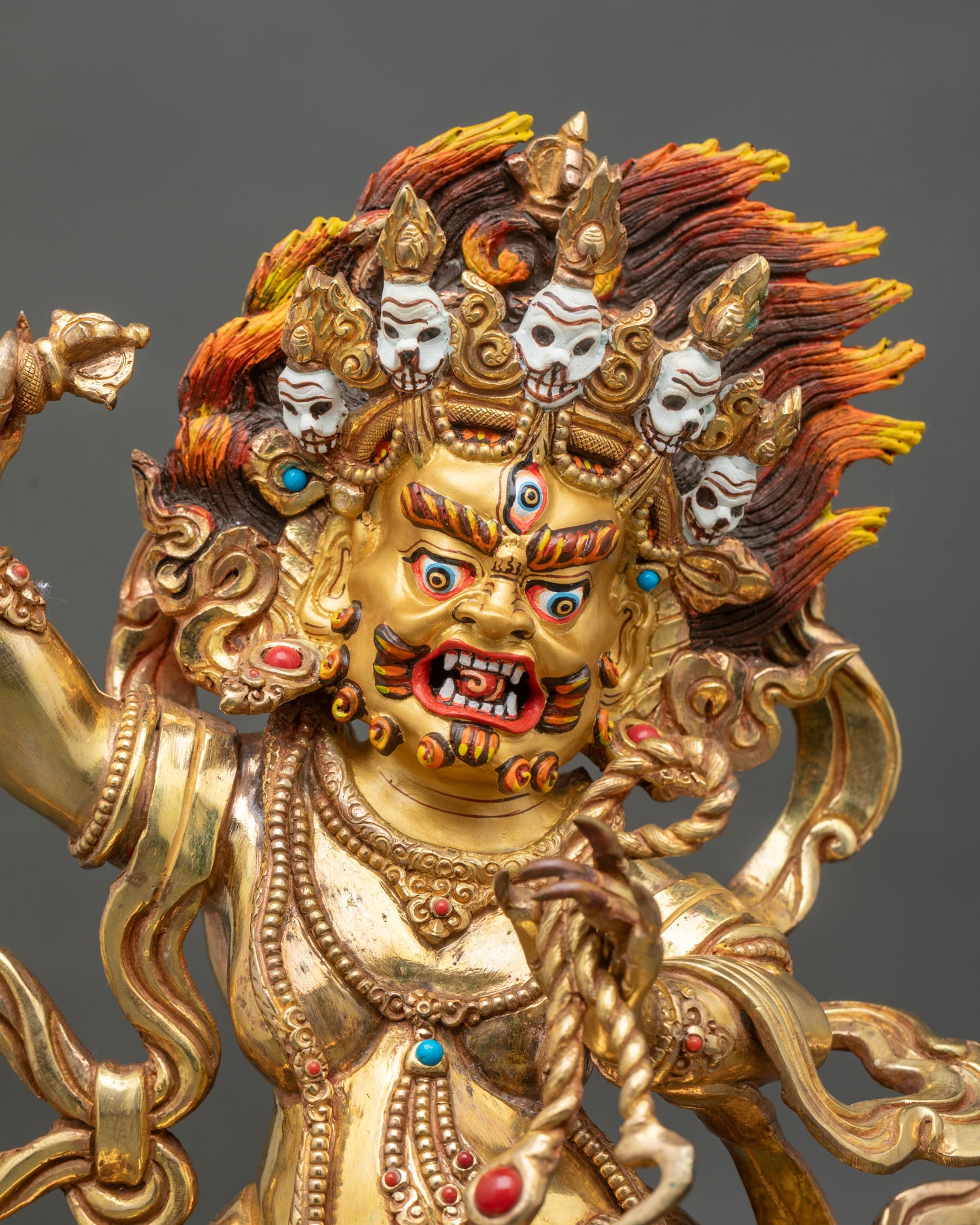 Close up Vajrapani statue gold-painted face five-skull diadem semi-precious stones