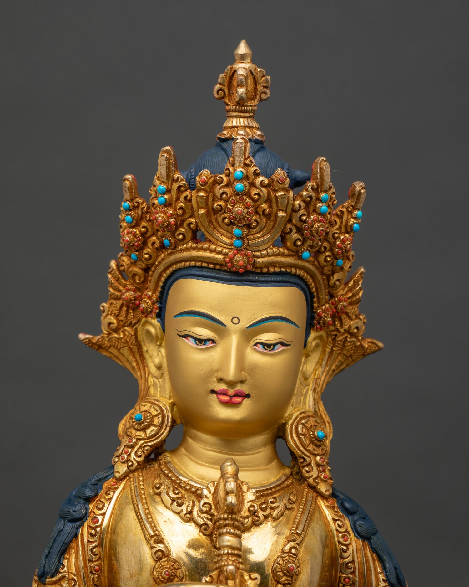 Close up Vajrasattva statue gold-painted face semi-precious stones intricate details