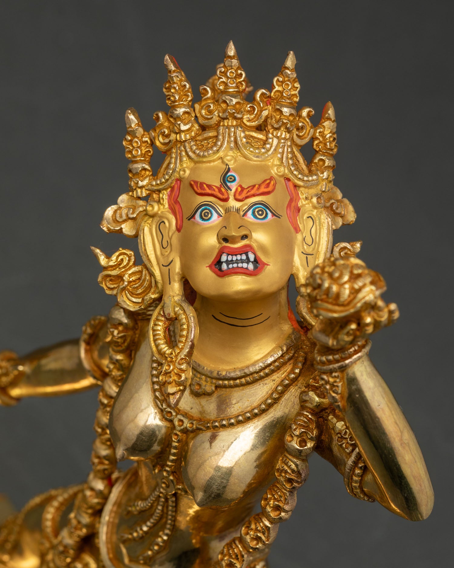 Close up Vajrayogini statue gold-painted face five-skull crown garland intricate details