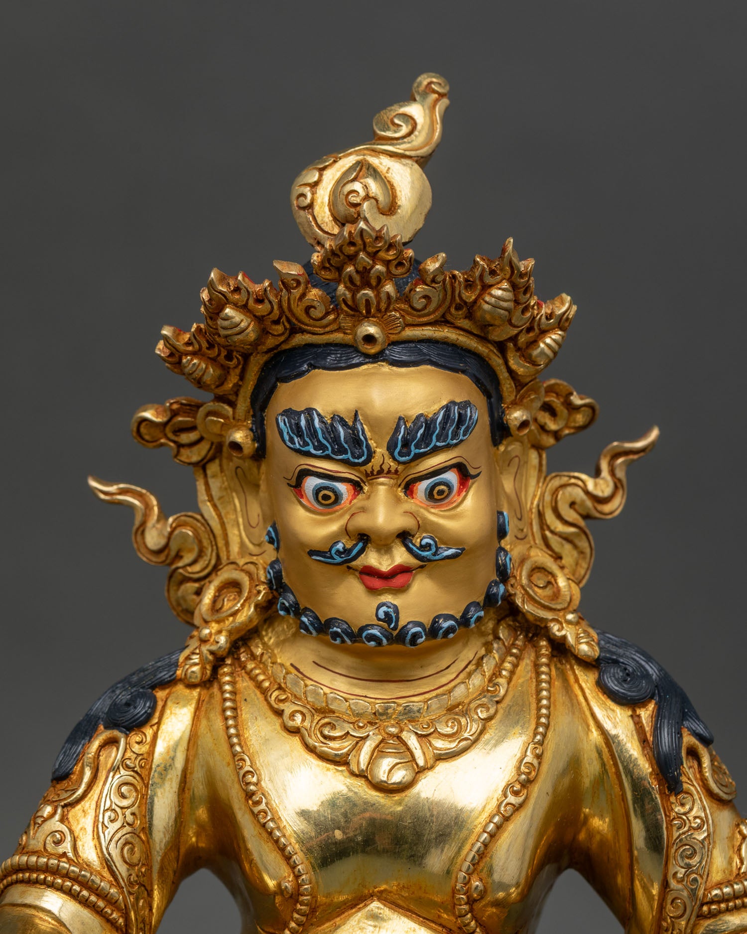 Close up of Dzambhala Statue 24k gold painted face mongoose in hand sacred Nepalese sculpture