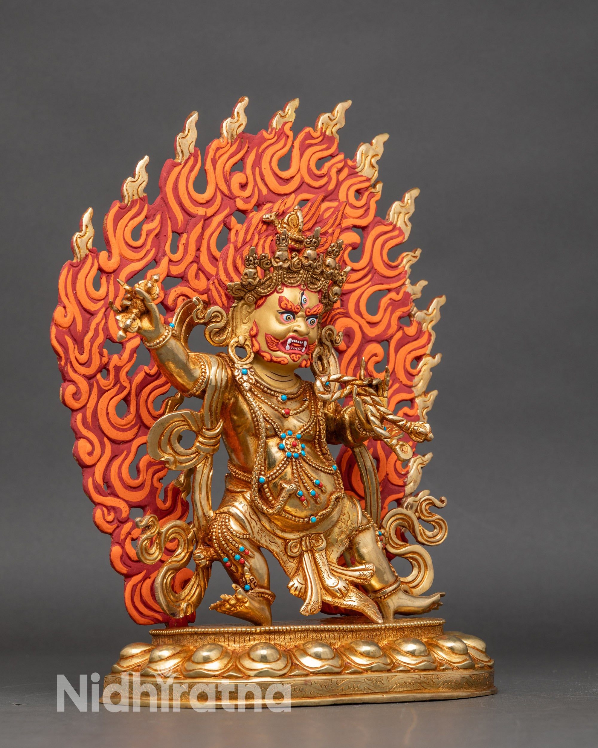Close-up of Vajrapani statue showing intricate gold fire-gilded details and halo colors