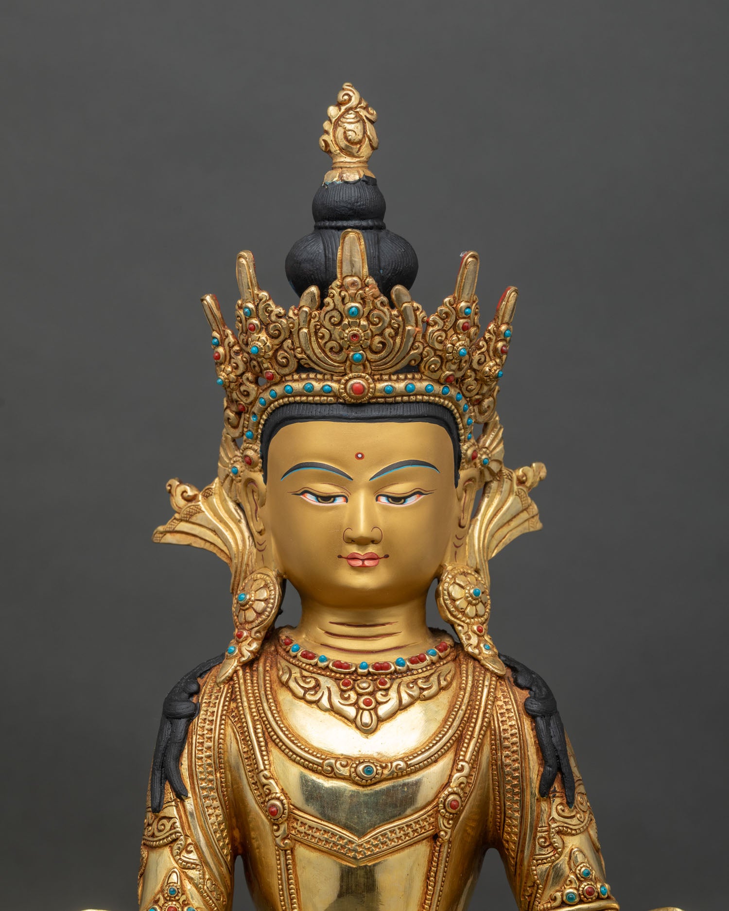 Close-up of crowned Shakyamuni Buddha statue showing intricate gold-gilded copper details