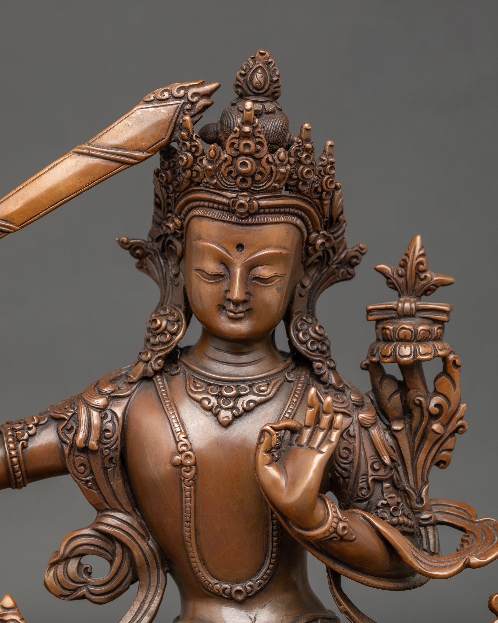 Close-up face – Detailed oxidized copper Manjushri statue face showing serene expression, symbolizing Buddhist wisdom and spiritual clarity.