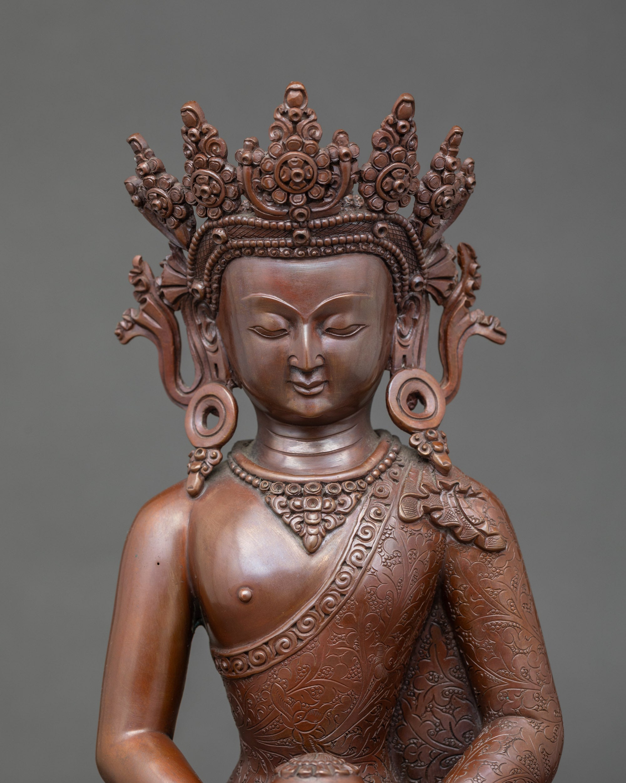Close-up of Amitabha Buddha’s serene face and diadem, oxidized copper Himalayan art