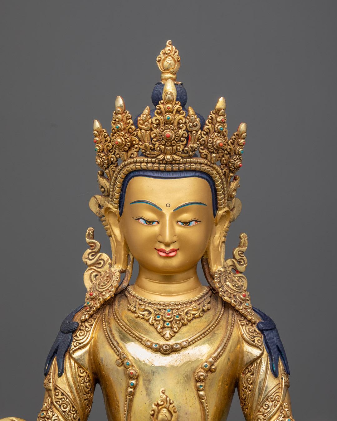 Close-up of Amitayus Buddha statue’s serene face with golden gilding and detailed ornamentation, handcrafted by Himalayan artisans.
