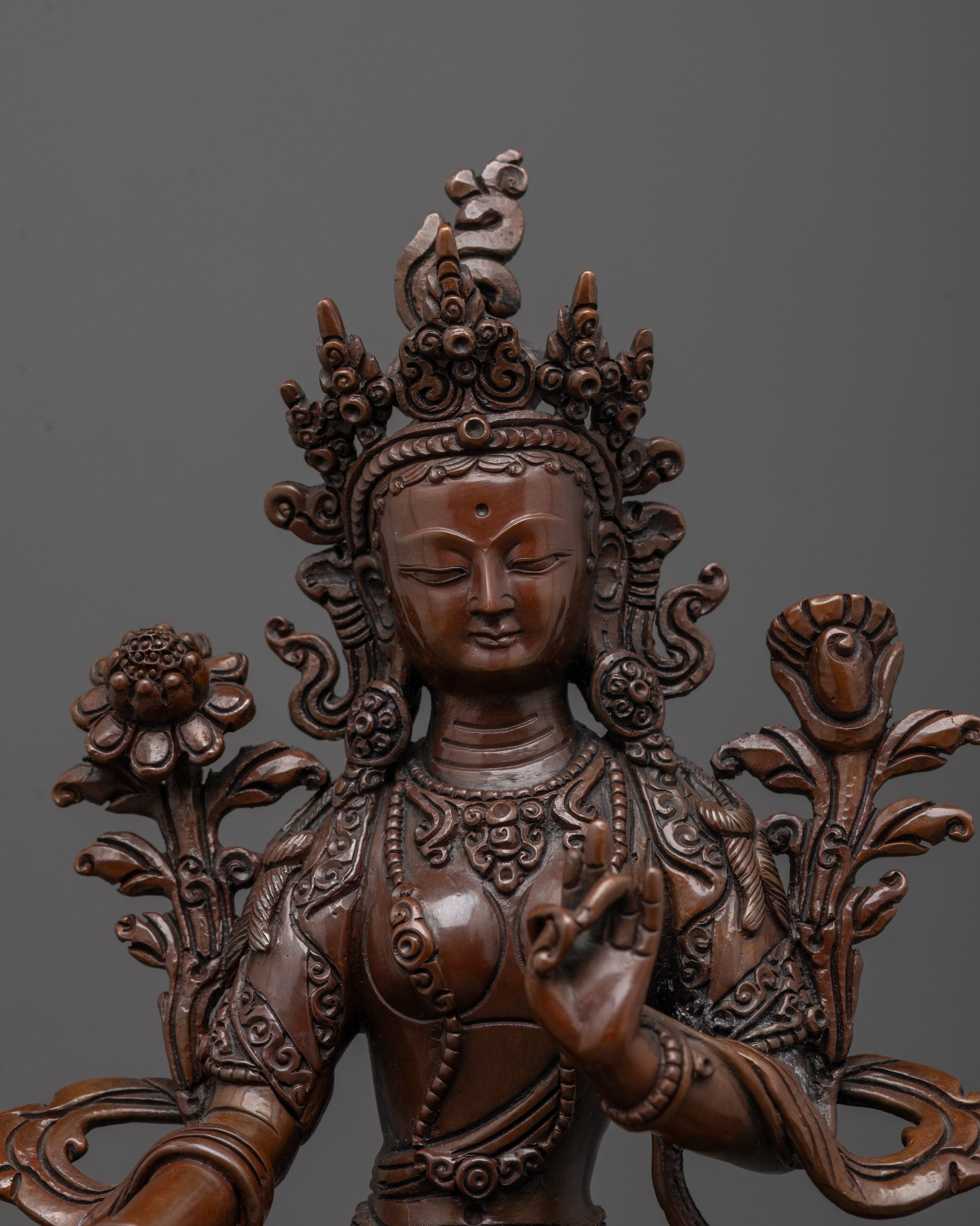 Close-up of Arya Tara's face showing oxidized copper finish and ornate crown