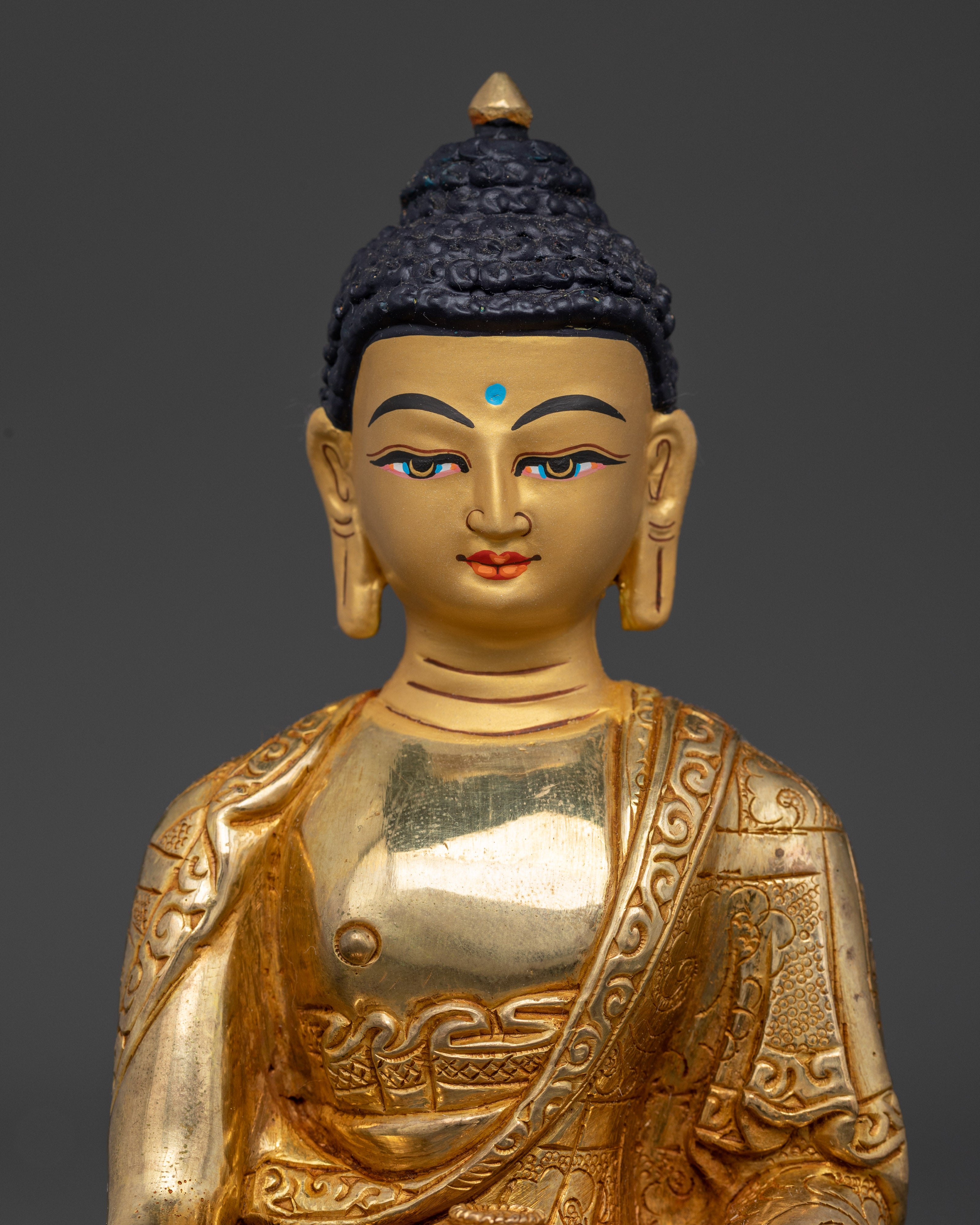 Close-up of Buddha Sakyamuni statue showing detailed monastic robes and fire-gilded face